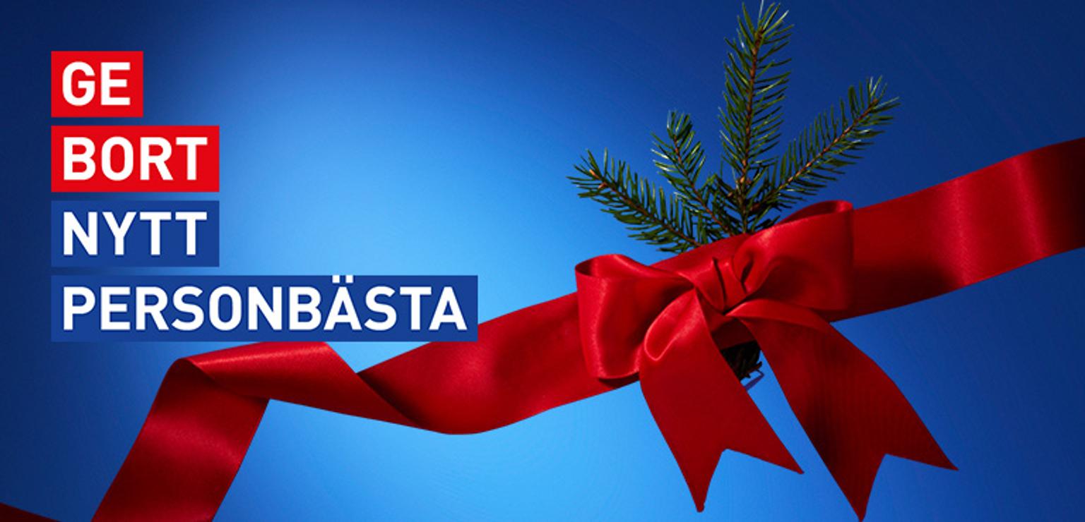 A red ribbon bow with pine sprigs on a blue background, overlaid with the Swedish text "GE BORT NYTT PERSONBÄSTA" (GIVE AWAY NEW PERSONAL BEST).
