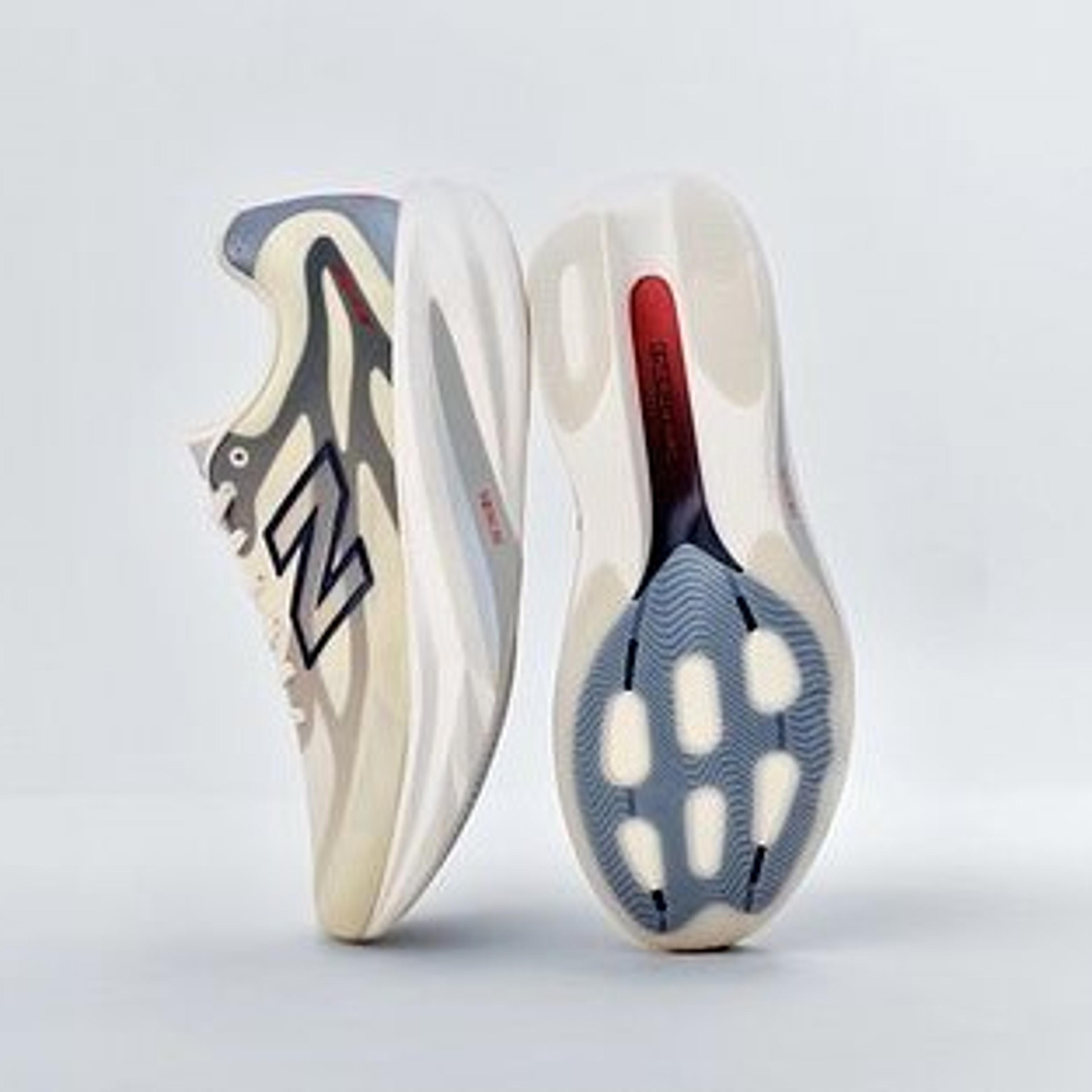 Two New Balance sneakers, one showing its side with a cream, grey, and blue wavy pattern and N logo, the other displaying its translucent sole with a blue textured grip and red accent.