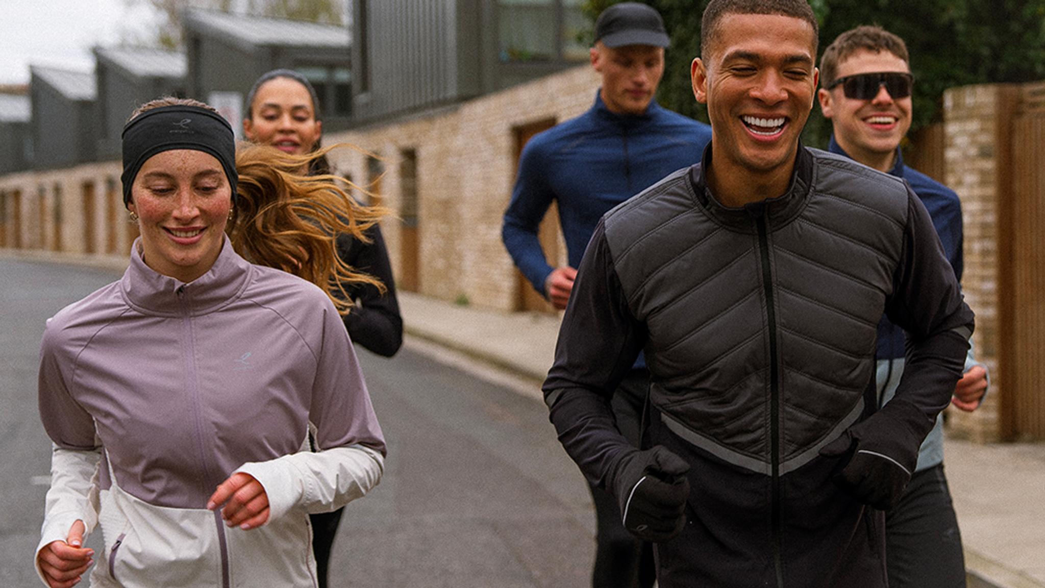 a group of people are running down a street in cold weather .