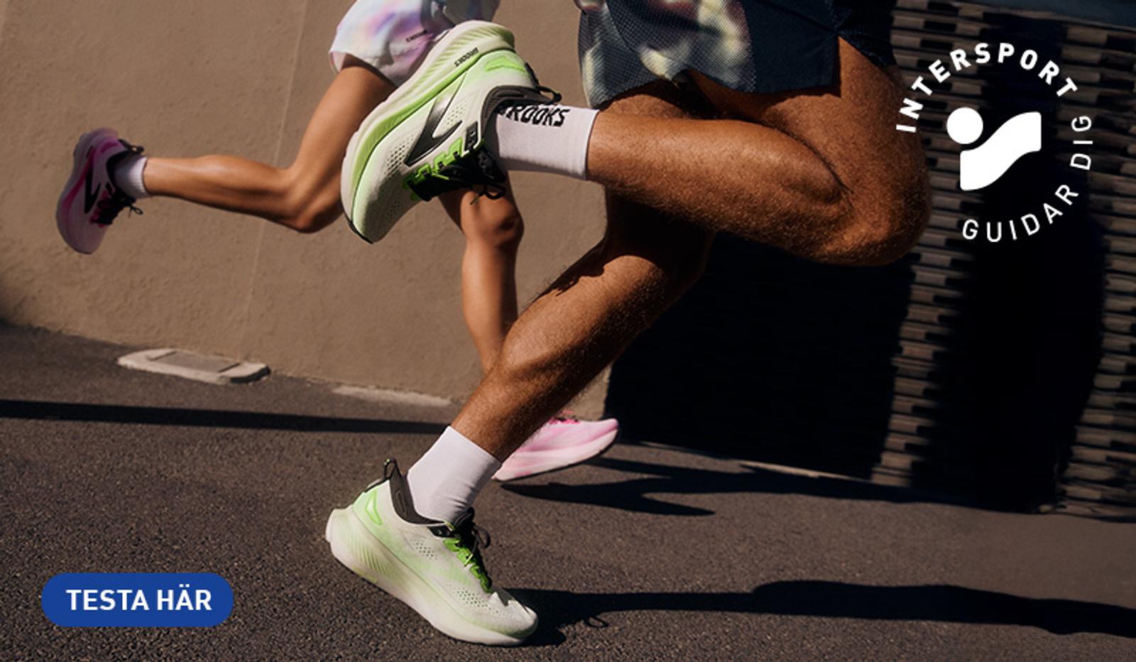 Two runners' legs in action, wearing green and white Brooks shoes and pink shoes. Intersport logo and 'TESTA HÄR' button are visible.