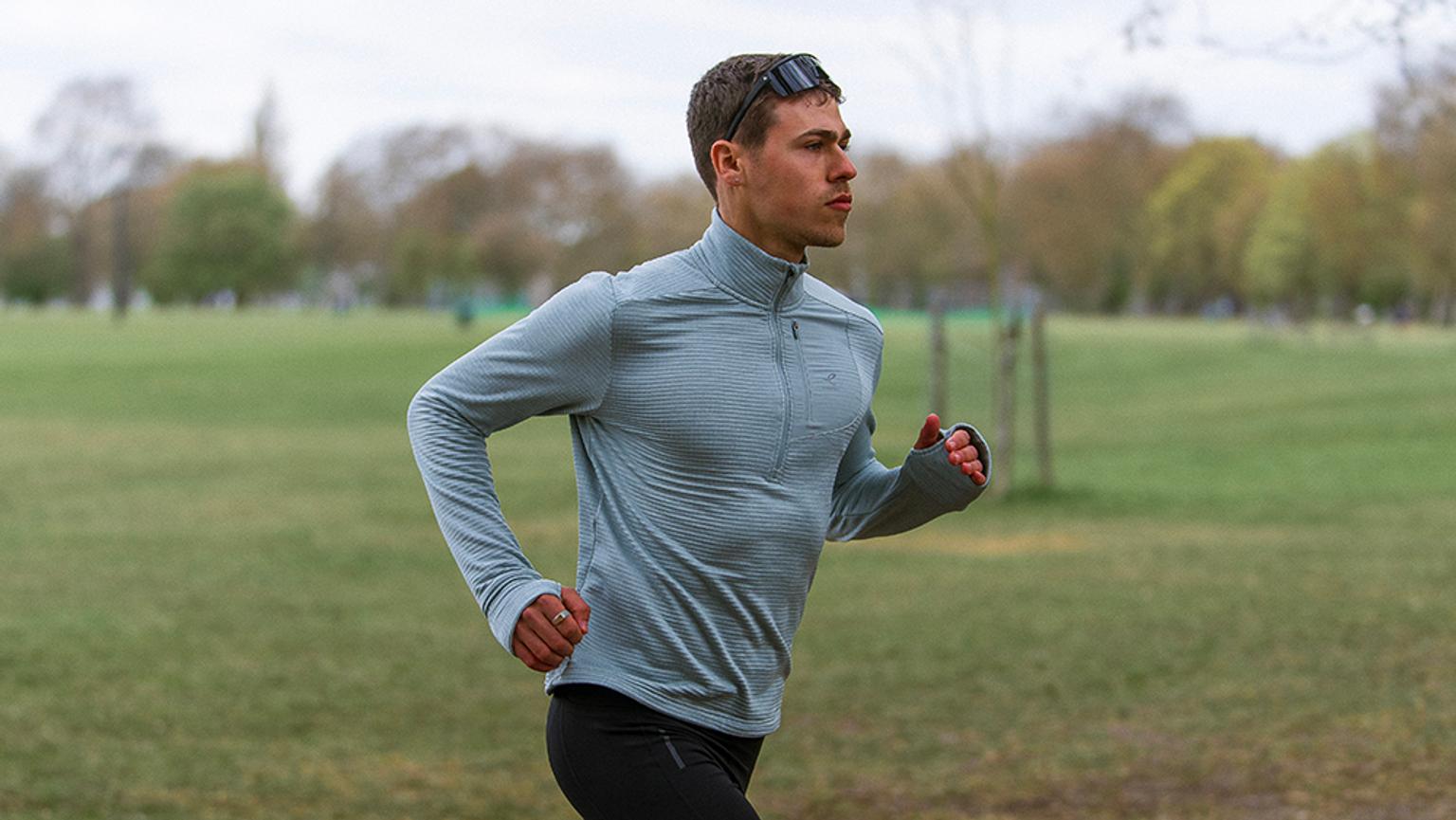 a man is running in a park wearing sunglasses and a blue shirt .