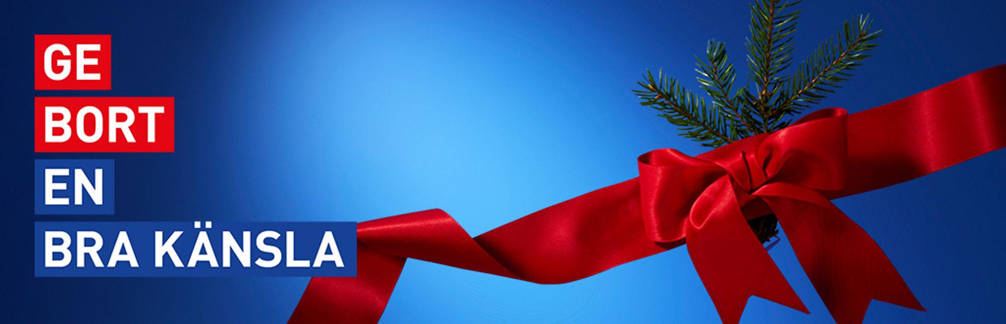 Red ribbon bow and pine sprig on a blue background, with the Swedish text 'GE BORT EN BRA KÄNSLA' (GIVE A GOOD FEELING).