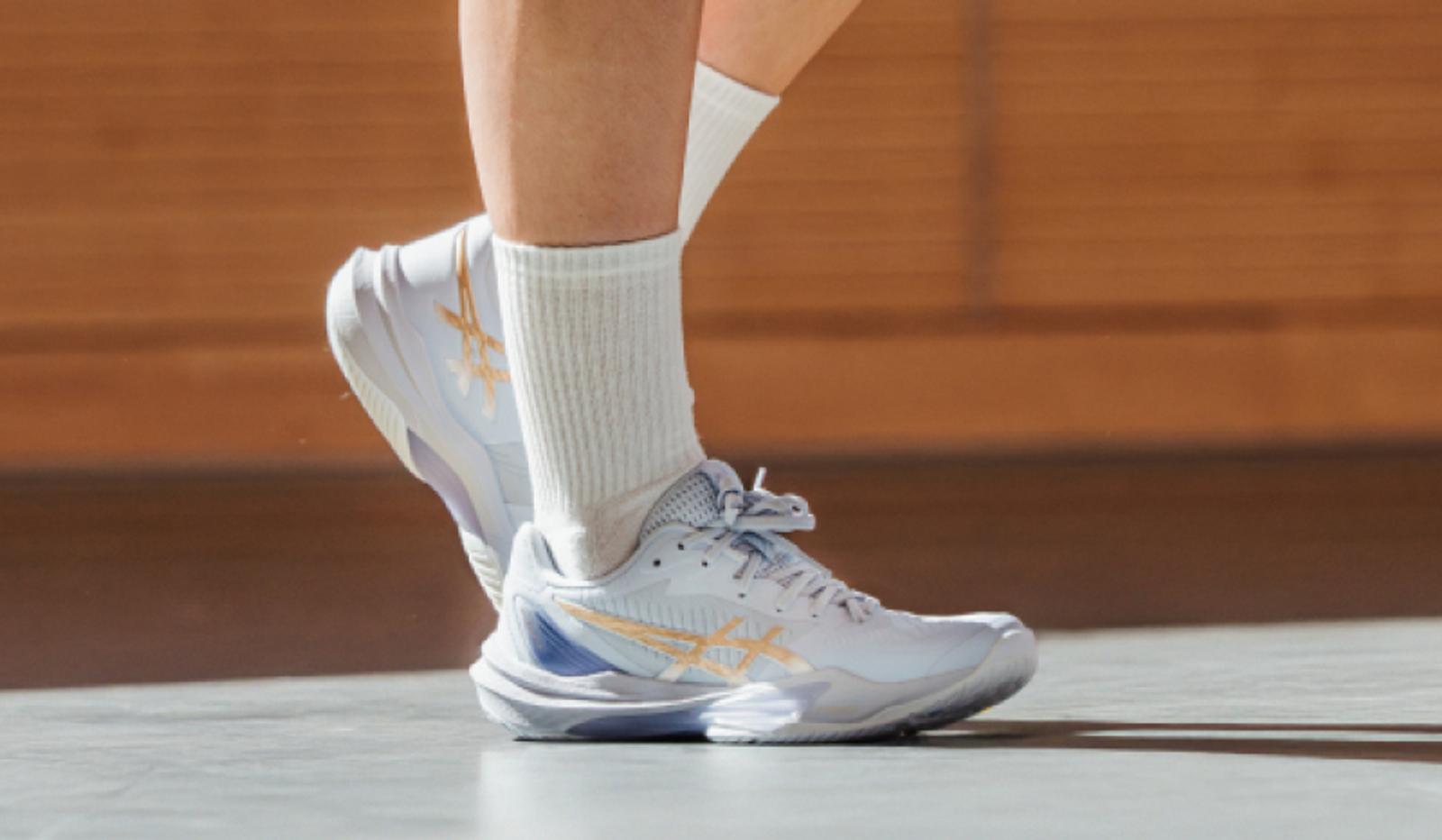 a person wearing a pair of white sneakers and white socks .