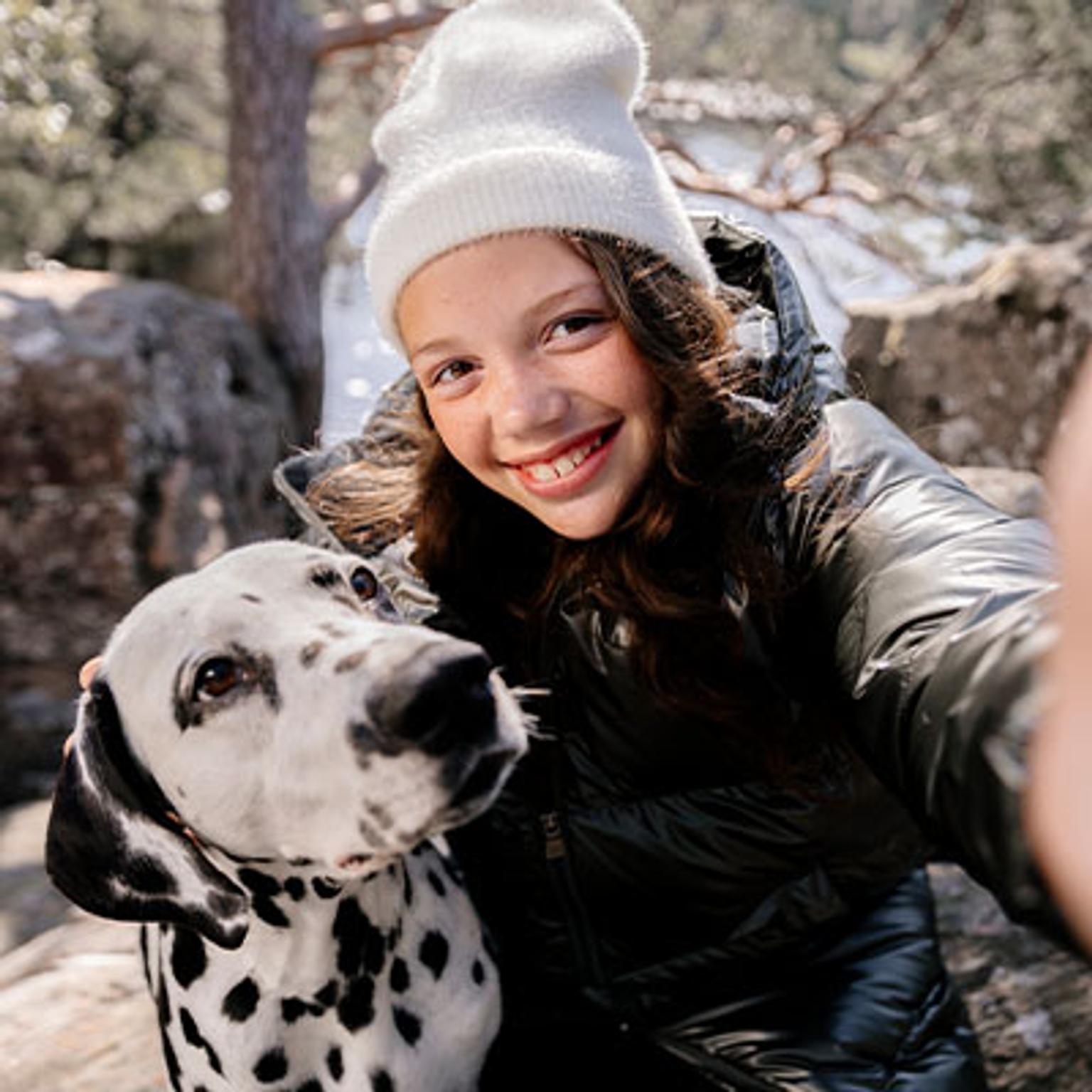 a young girl is taking a selfie with a dalmatian dog .