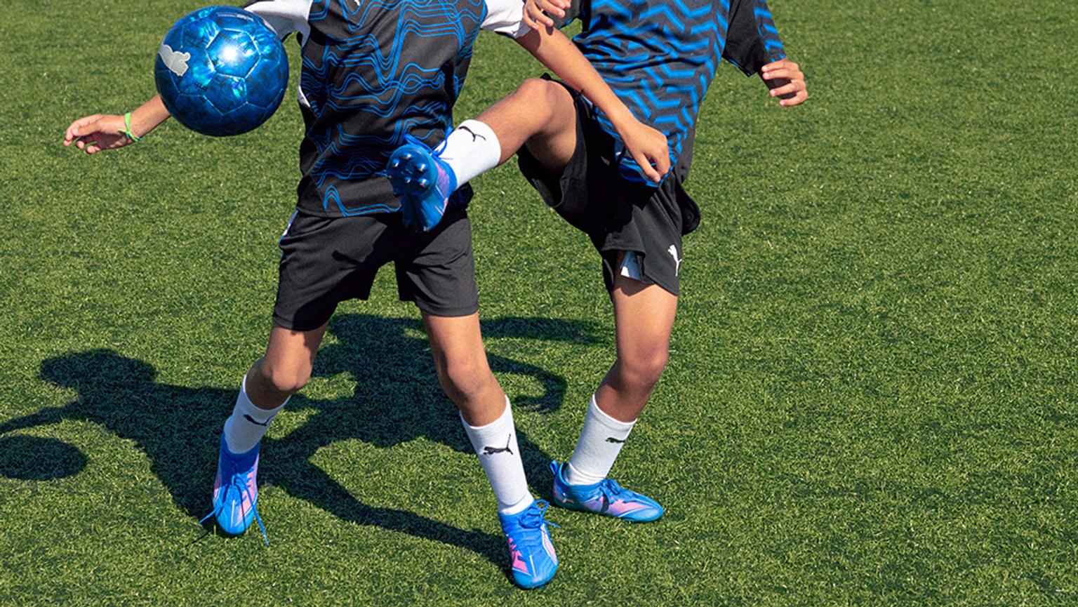 two young boys are playing soccer on a field .