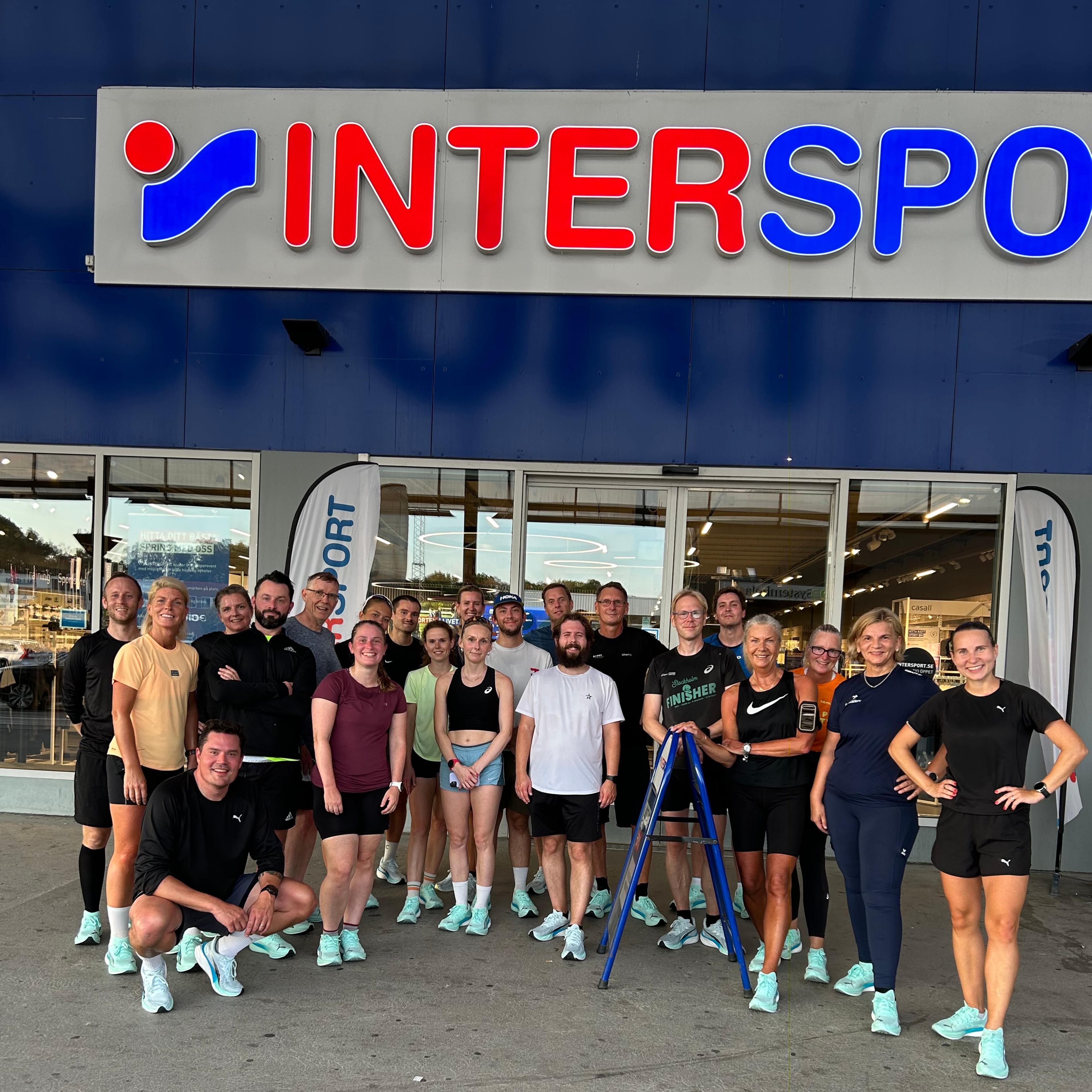 a group of people posing in front of an intersport store