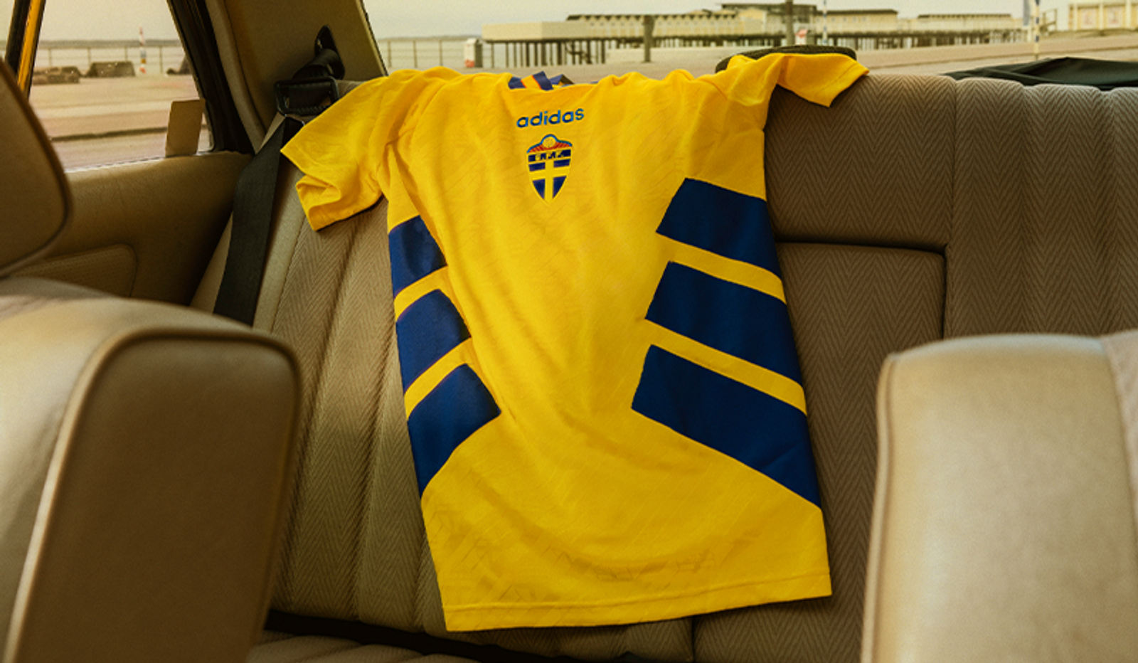 Back of a yellow Sweden football jersey draped over a car seat.