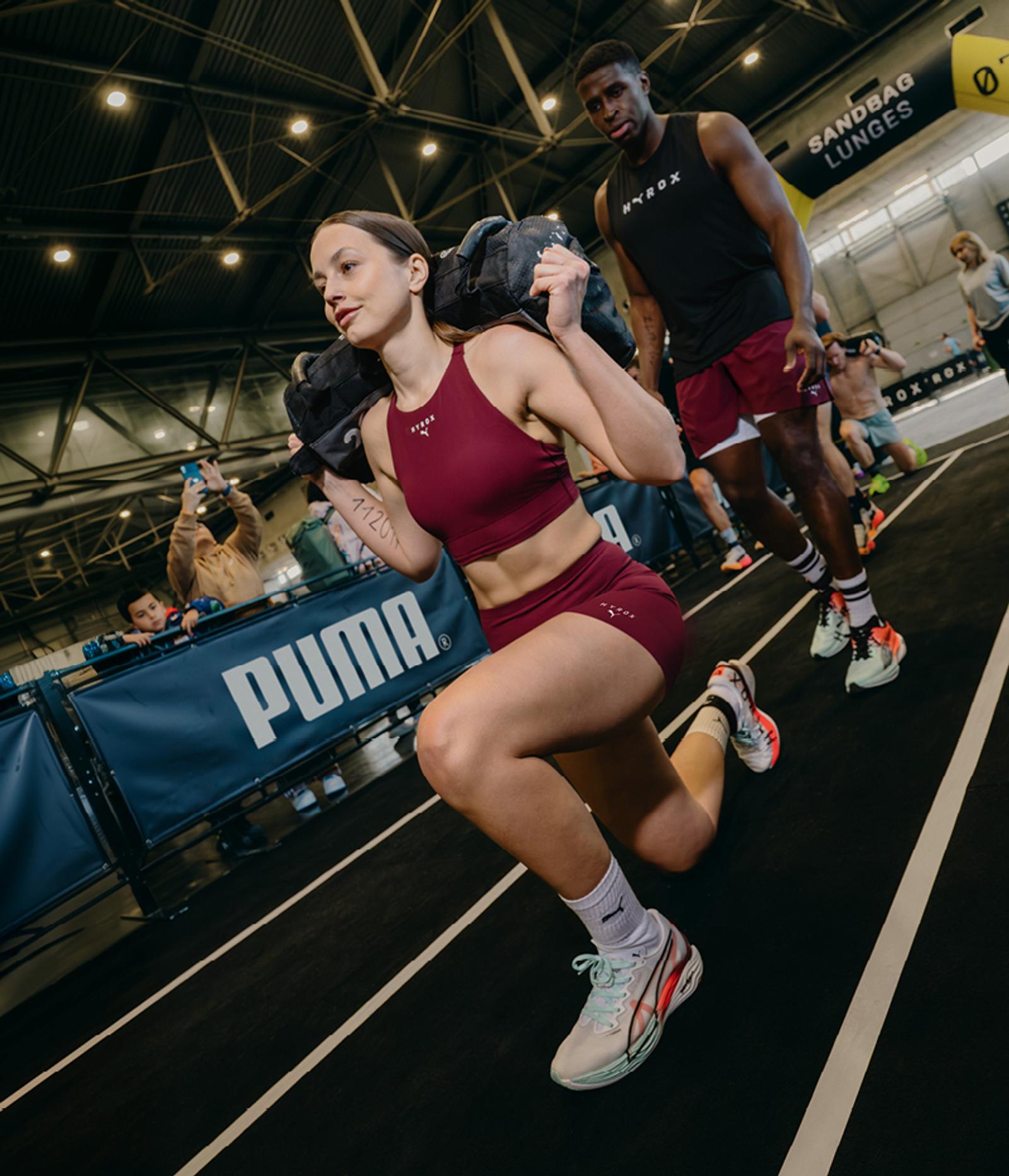 a woman squatting with a bag on her back in front of a puma banner