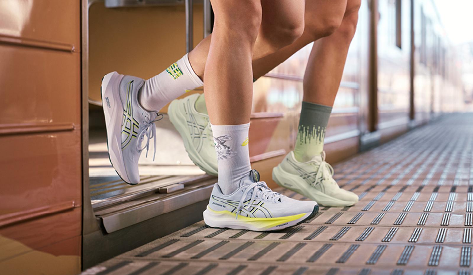 a couple of people wearing running shoes and socks are standing next to each other on a train .