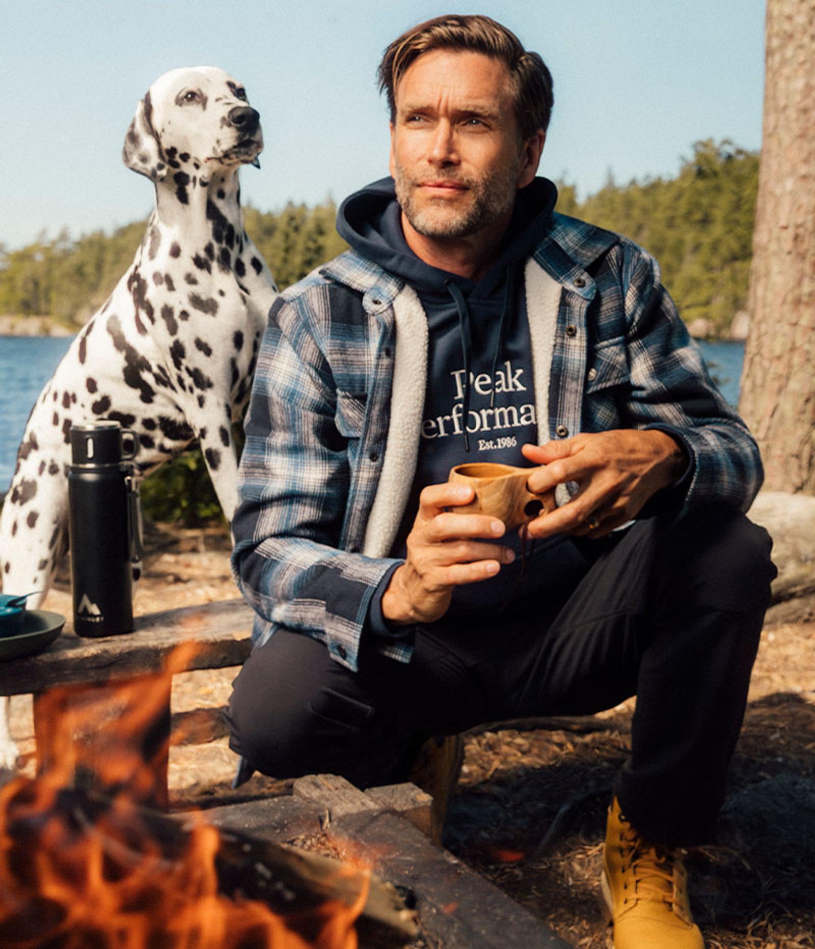 a dalmatian dog is sitting next to a man holding a cup of coffee .