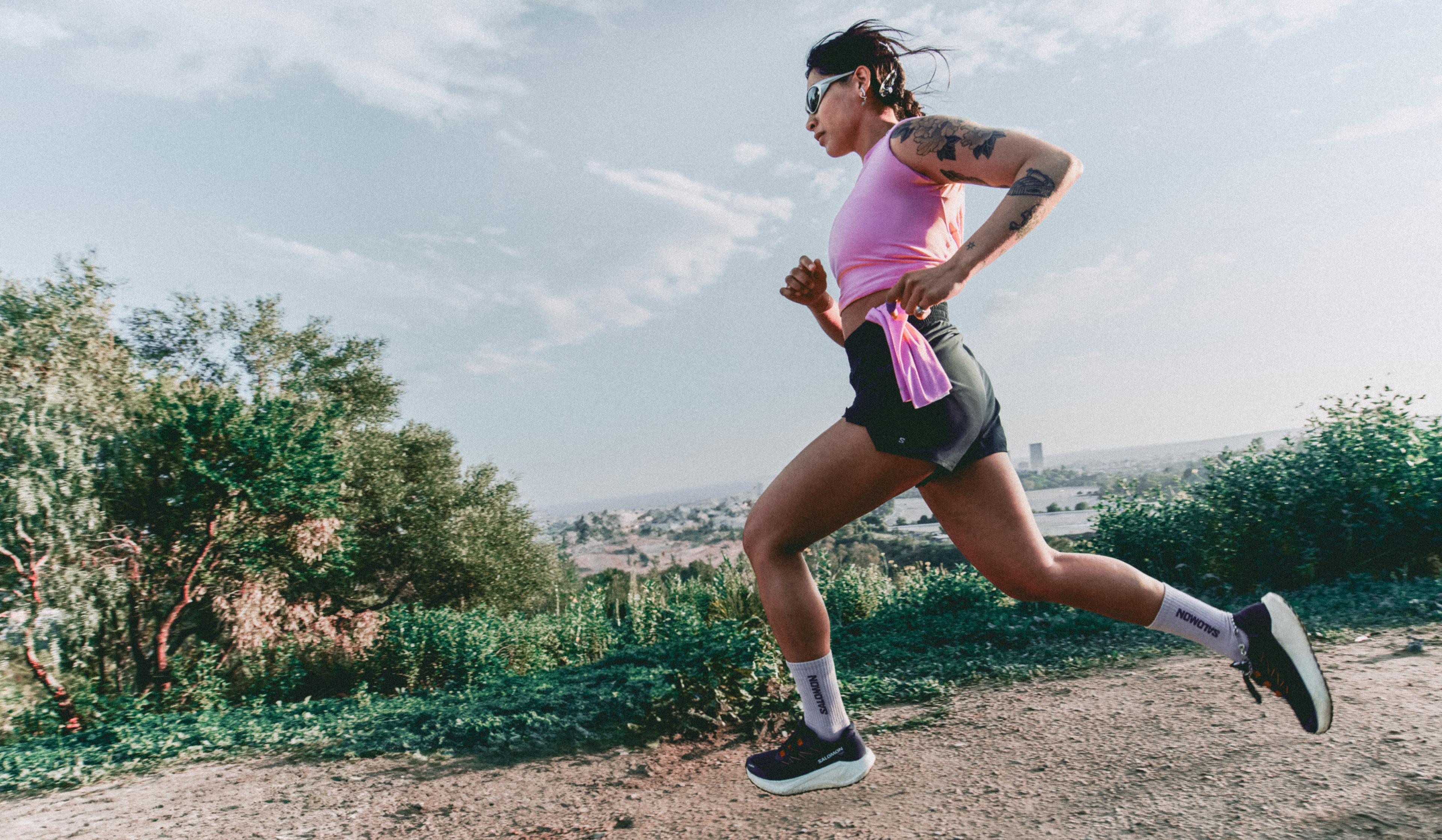 a woman is running on a dirt path in the woods .