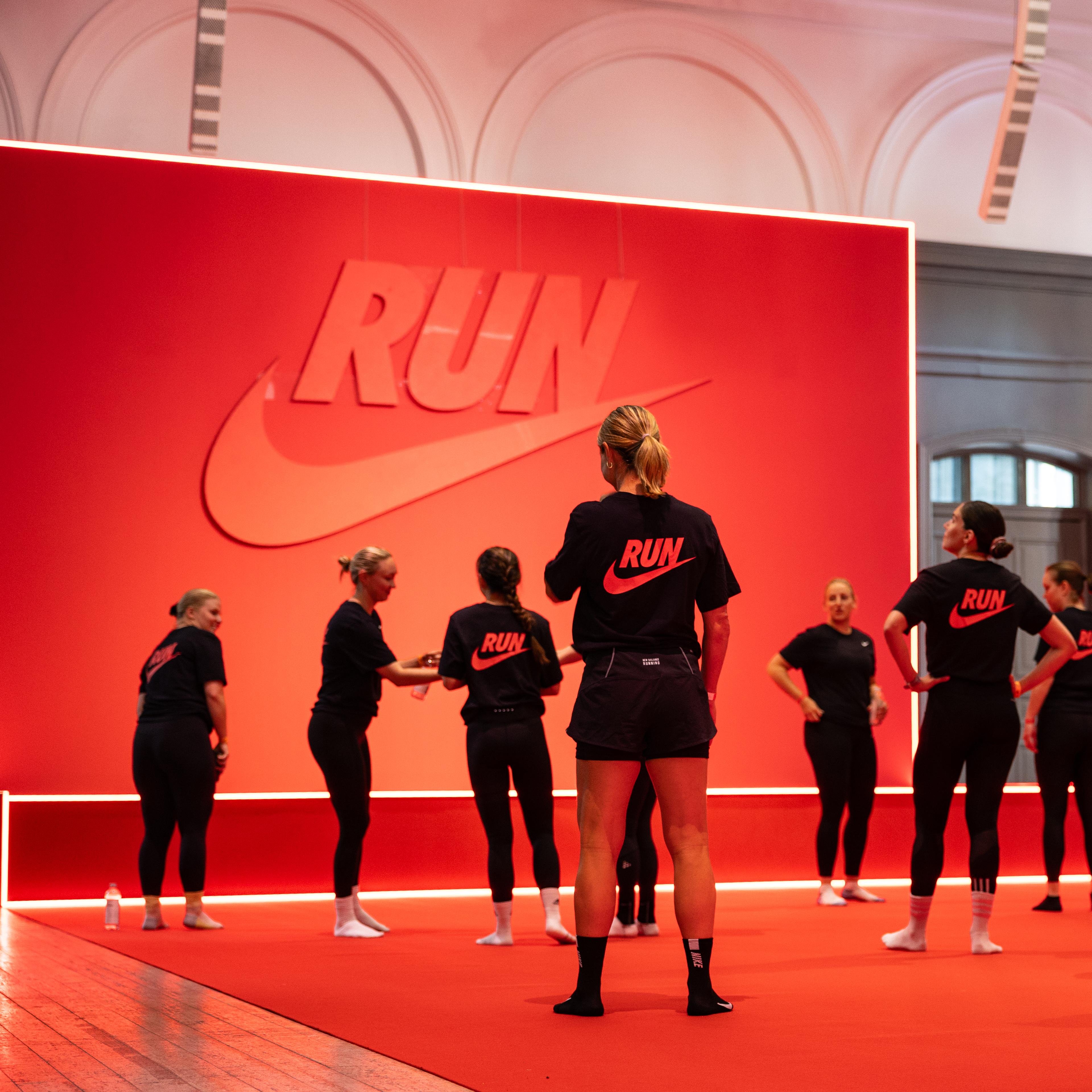 a group of women are standing on a red carpet in front of a large nike sign .