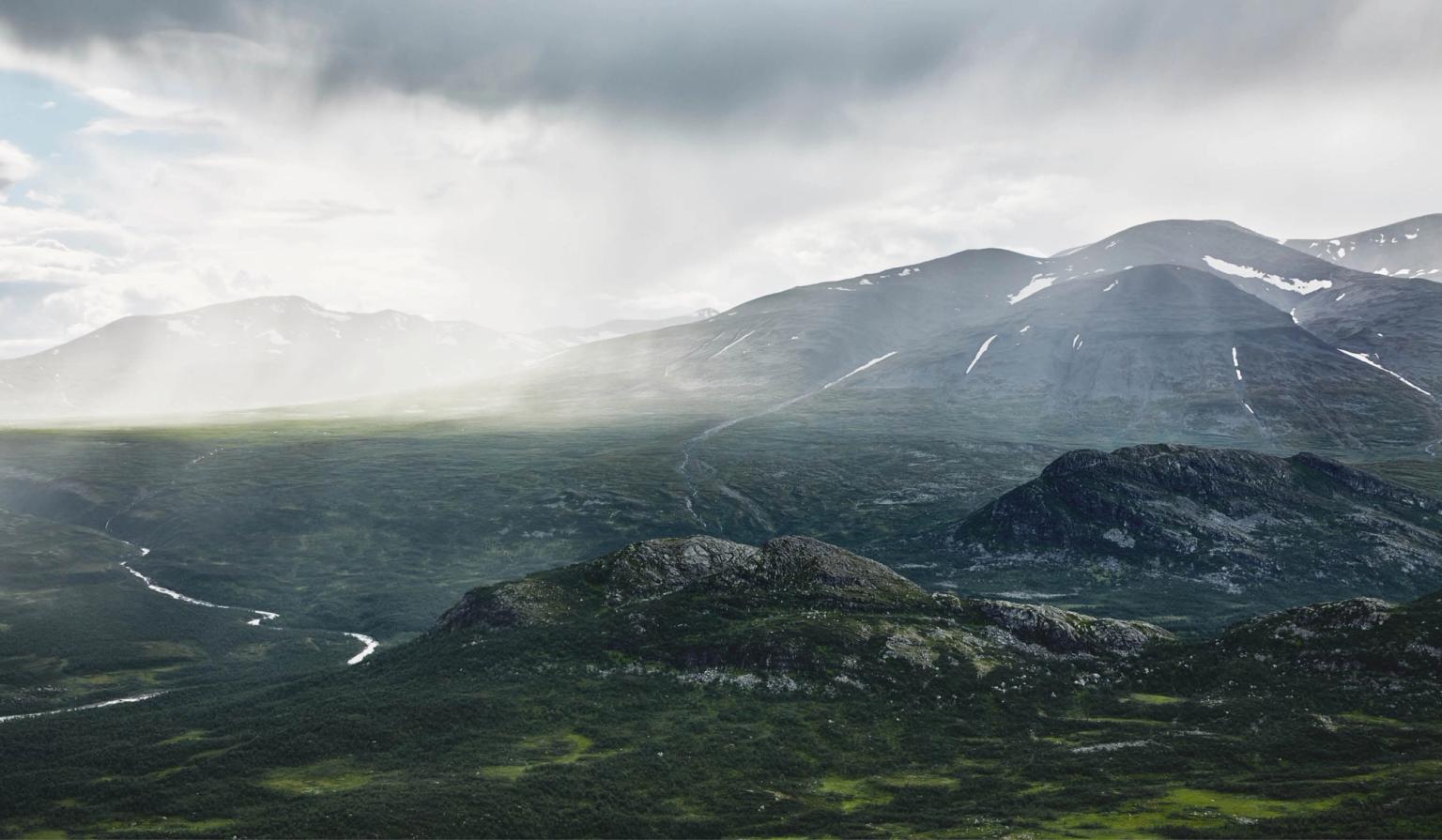 the sun is shining through the clouds over the mountains .