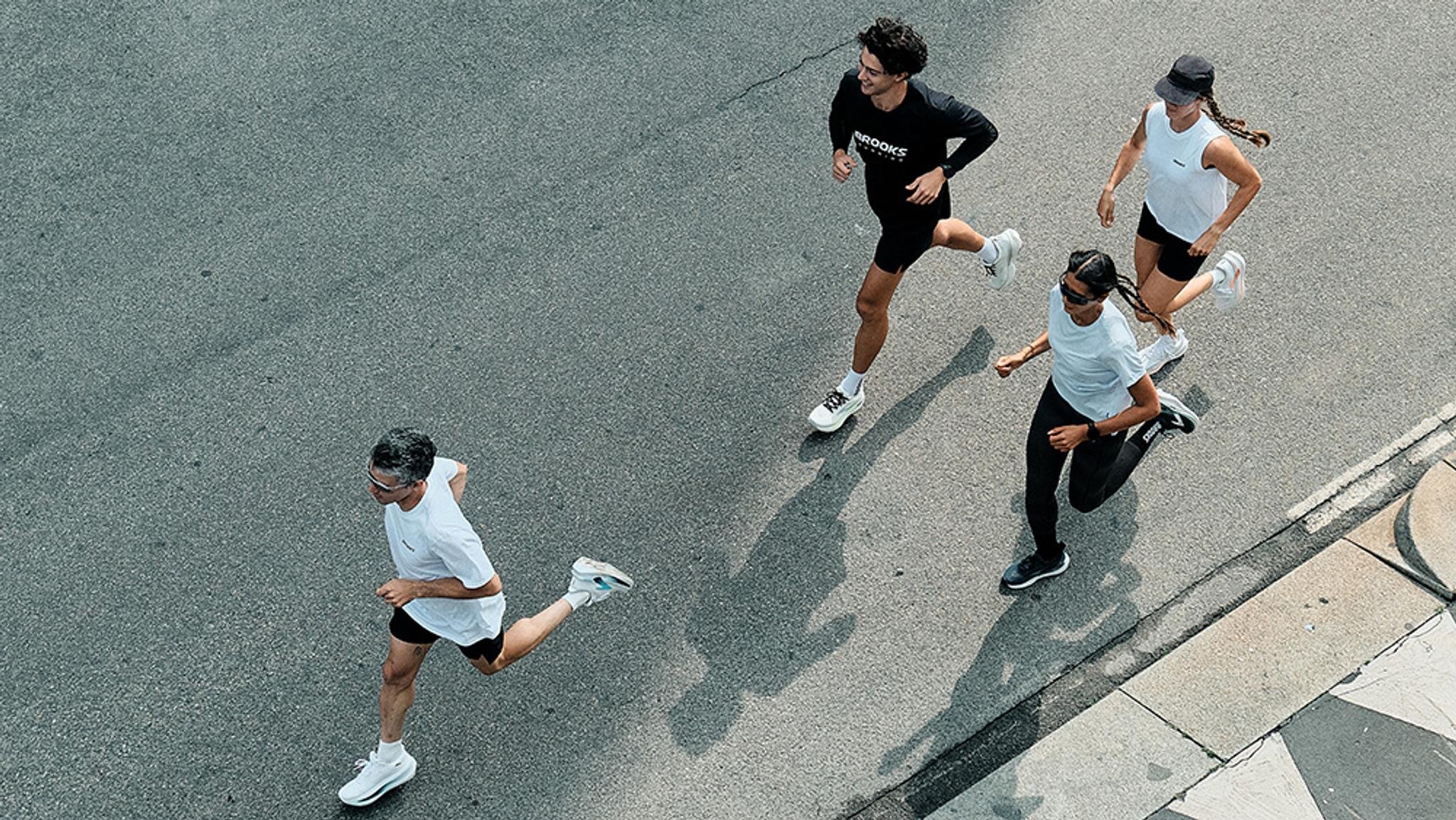 Overhead view of four people running on an asphalt road.