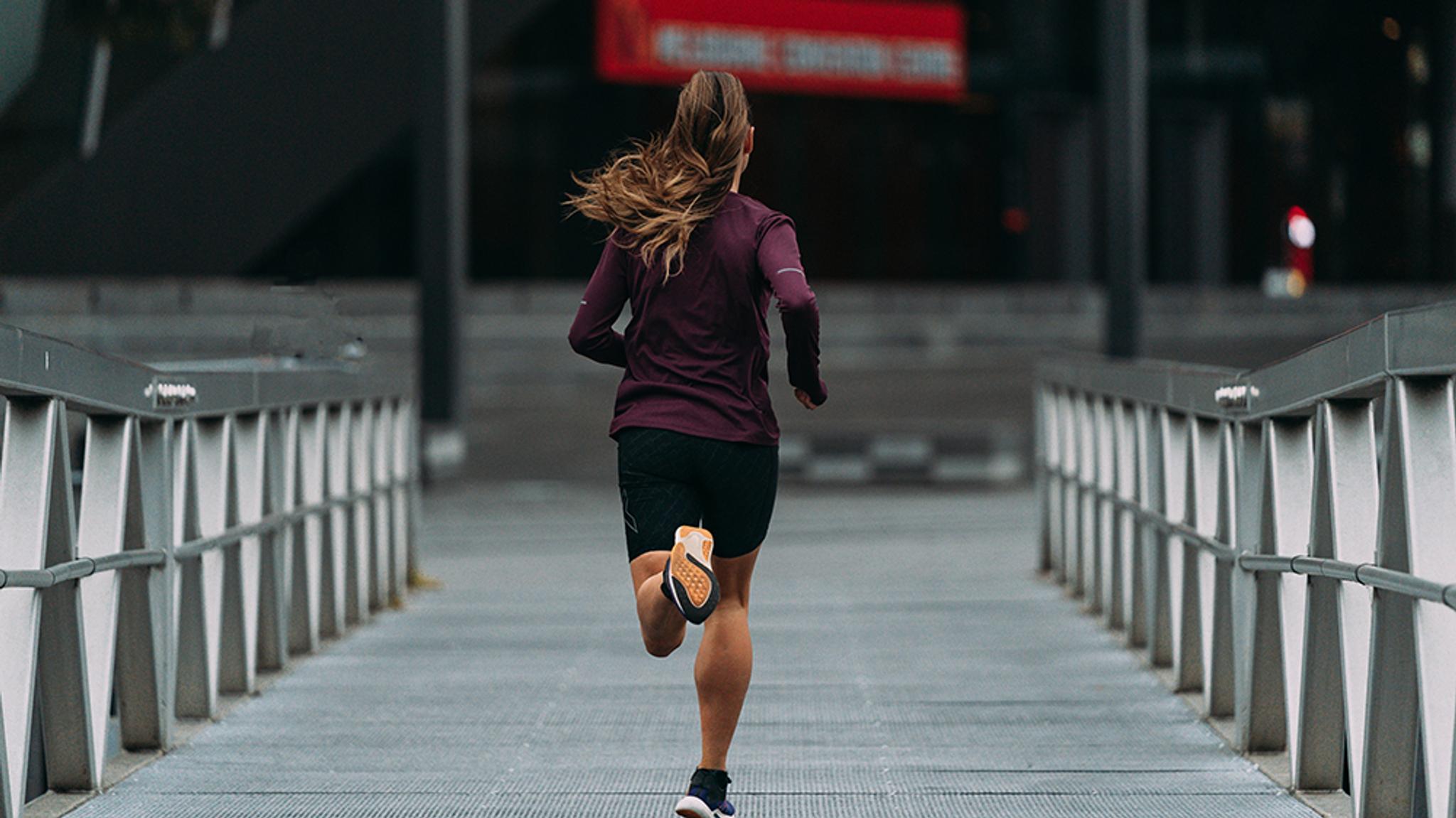 a woman is running on a bridge in the city .