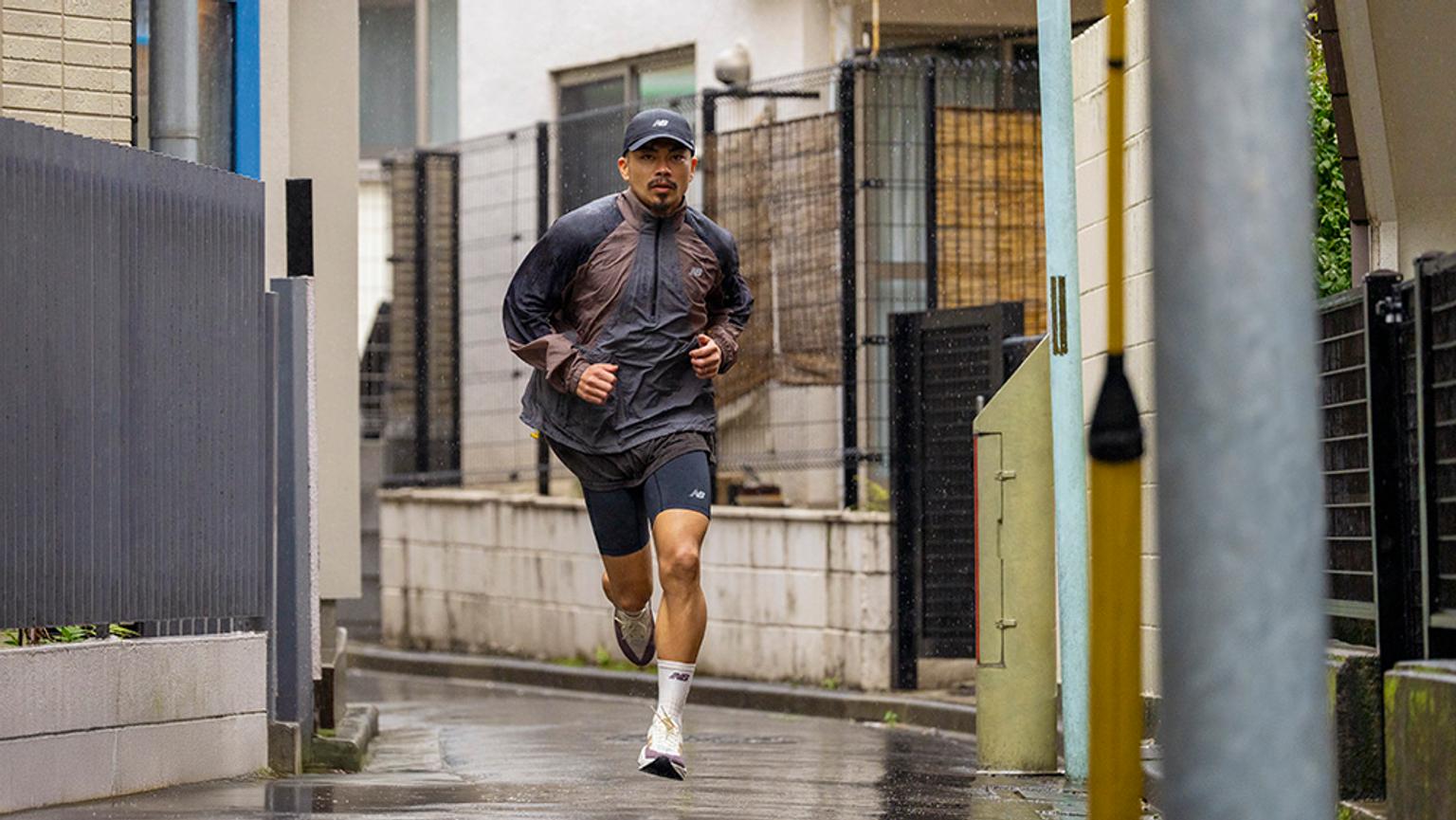 a man is running down a narrow street in the rain .