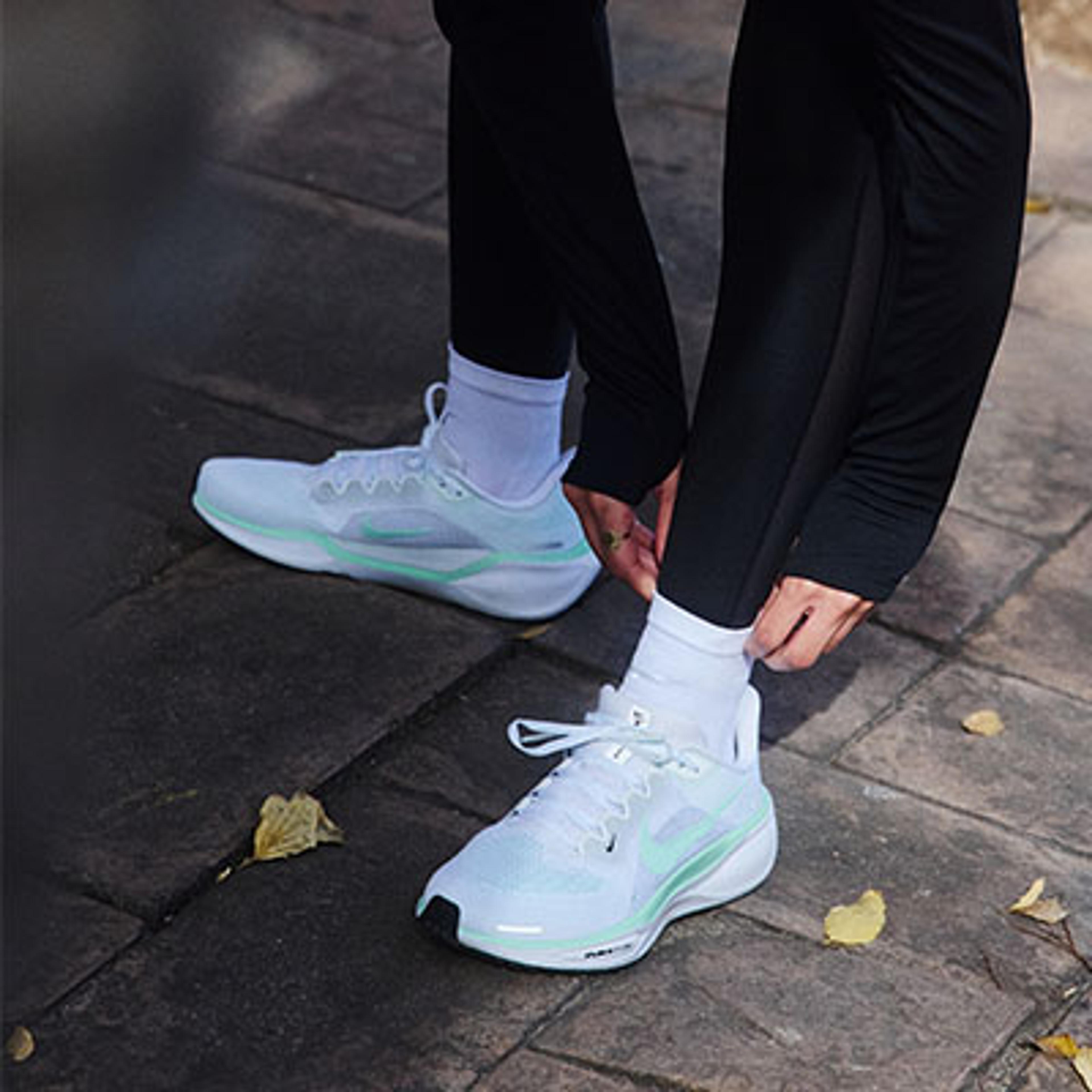 a person is tying their shoes on a sidewalk .