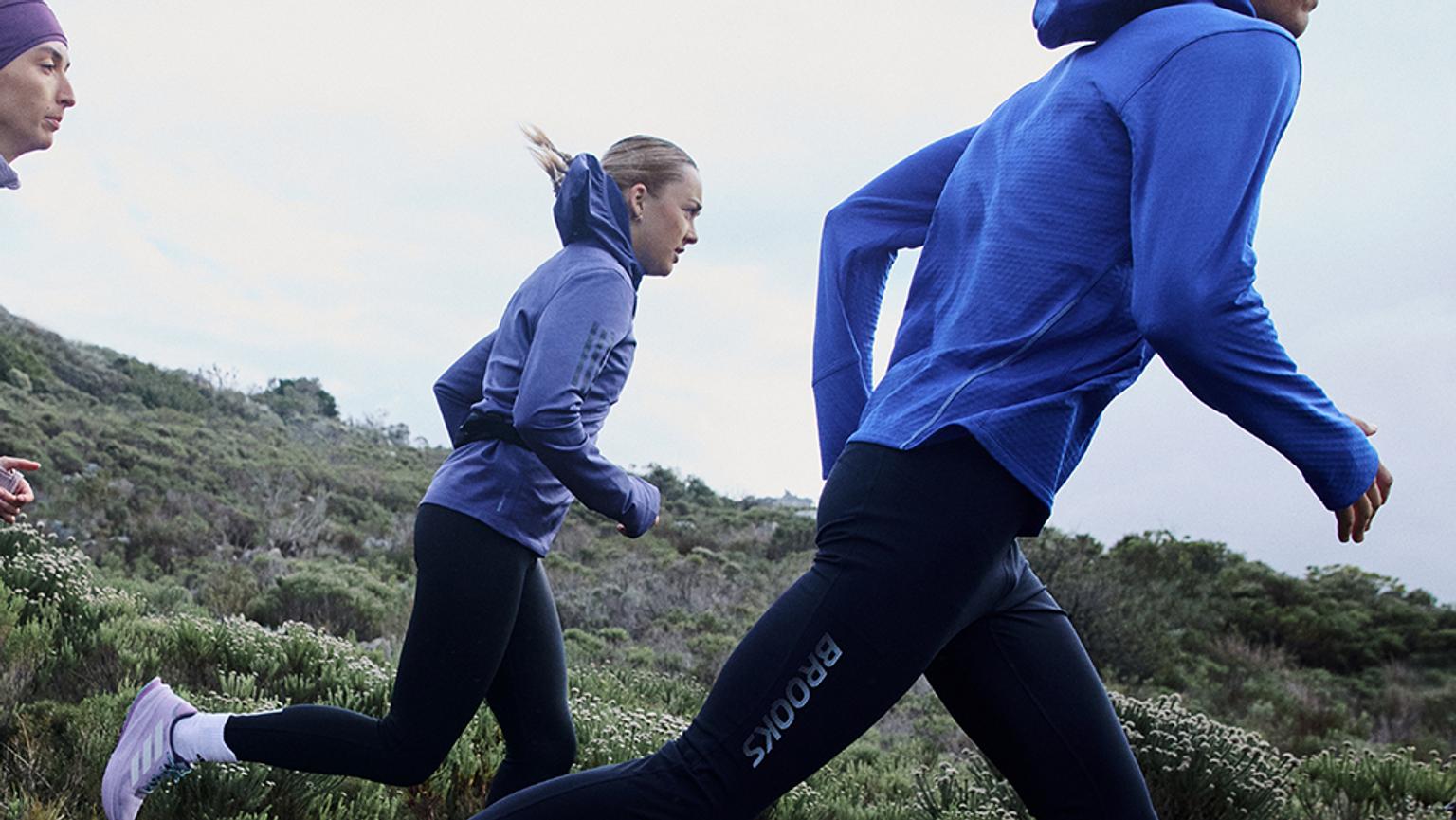 a group of people are running on a hill .