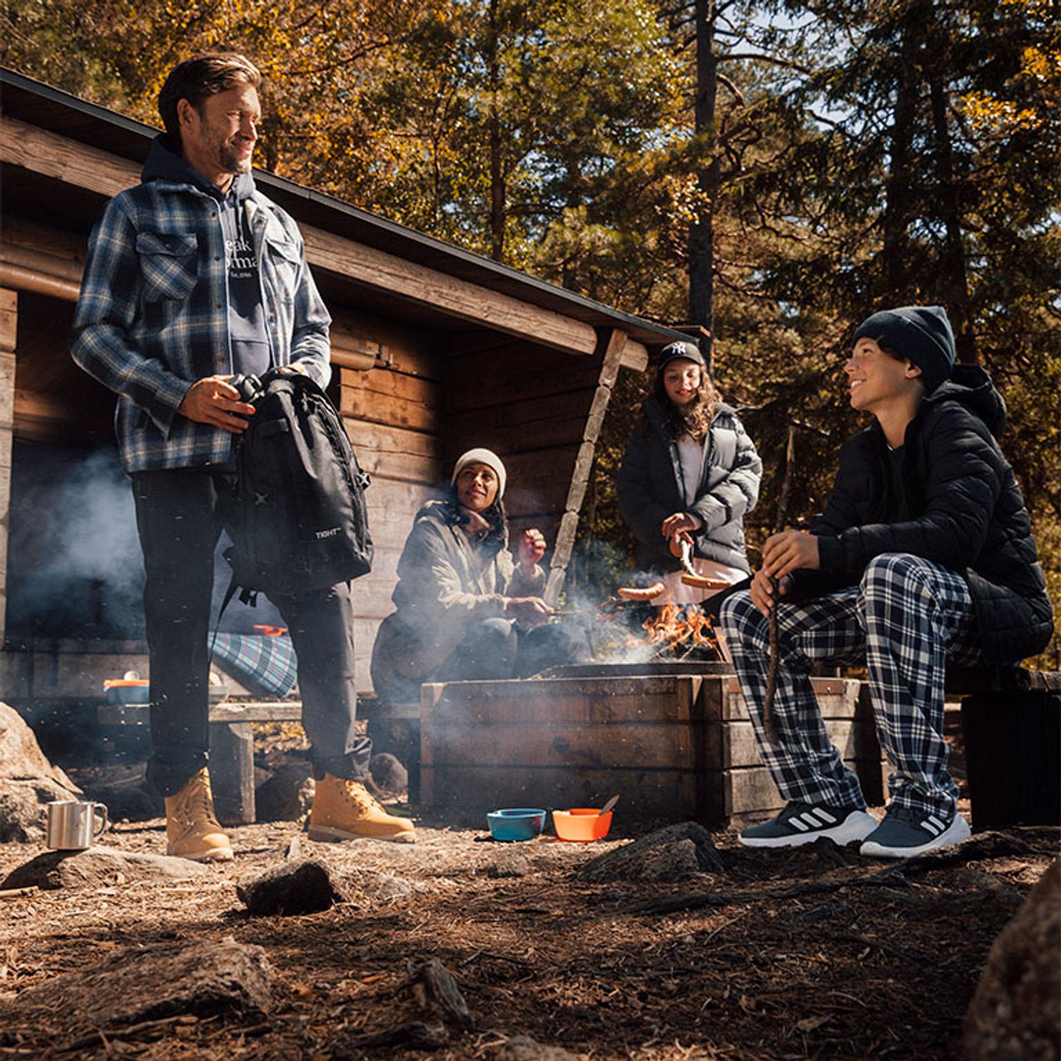 a group of people are sitting around a campfire in the woods .