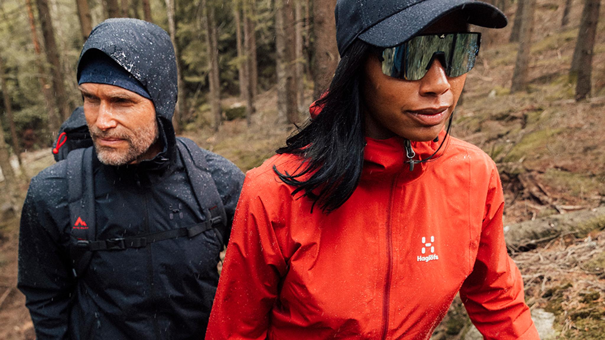a man and a woman are walking through a forest .
