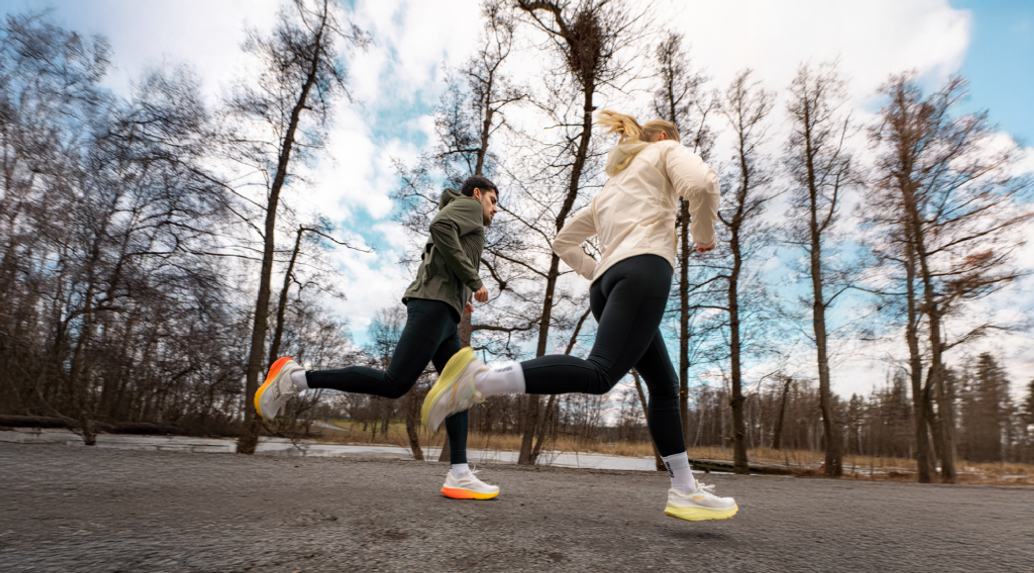 Two people running on a path through bare trees.