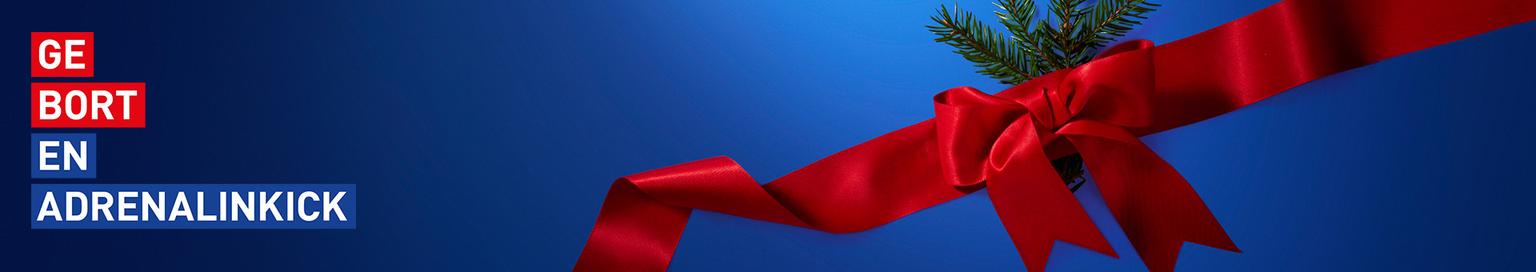 Blue banner with the Dutch text "GE BORT EN ADRENALINKICK" on the left, and a red bow with a pine branch on the right.