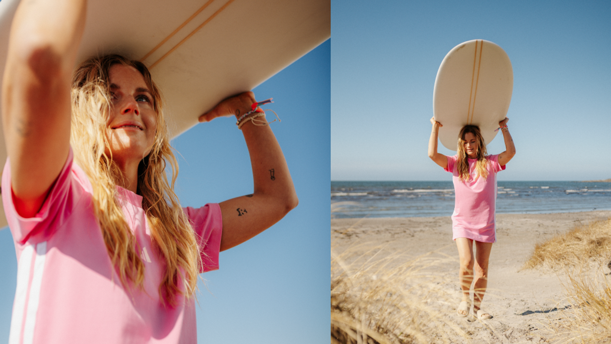 A blonde woman in a pink dress carries a surfboard over her head on a sunny beach.
