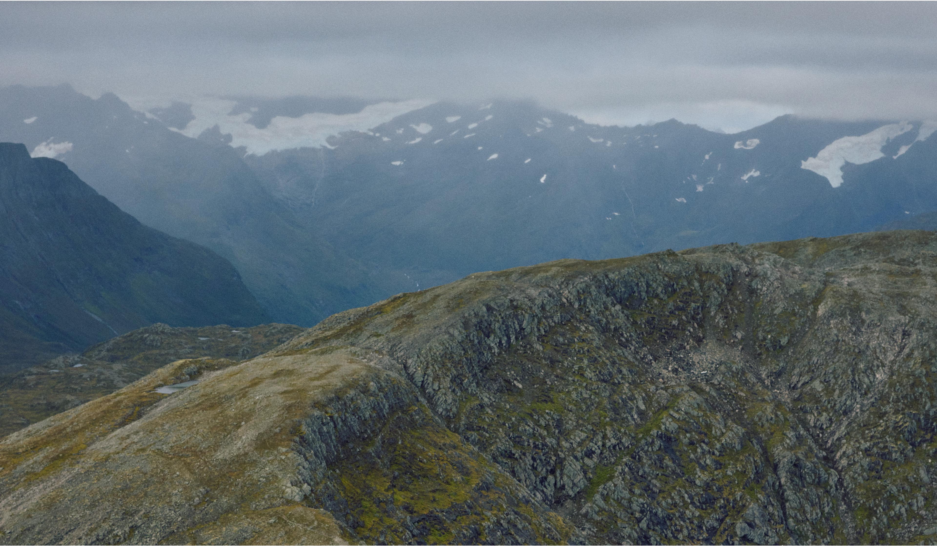 an aerial view of a mountain range on a cloudy day .