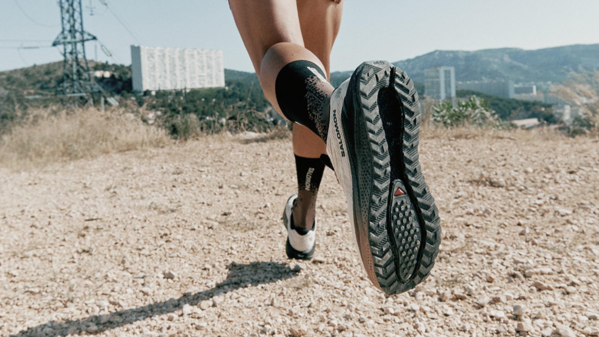 Close-up of a Salomon trail running shoe sole lifting off a gravel path.