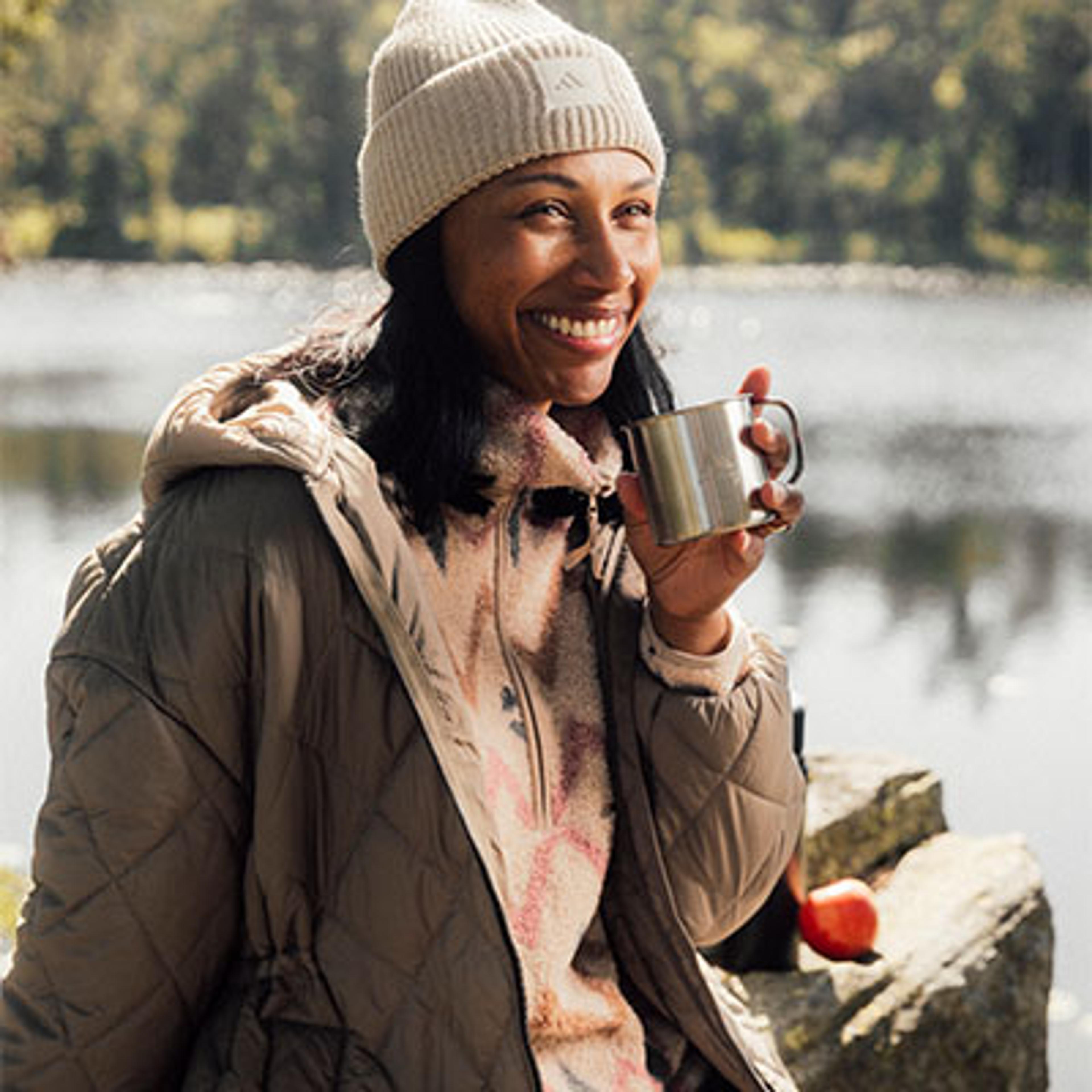 a woman is sitting on a rock holding a cup of coffee .