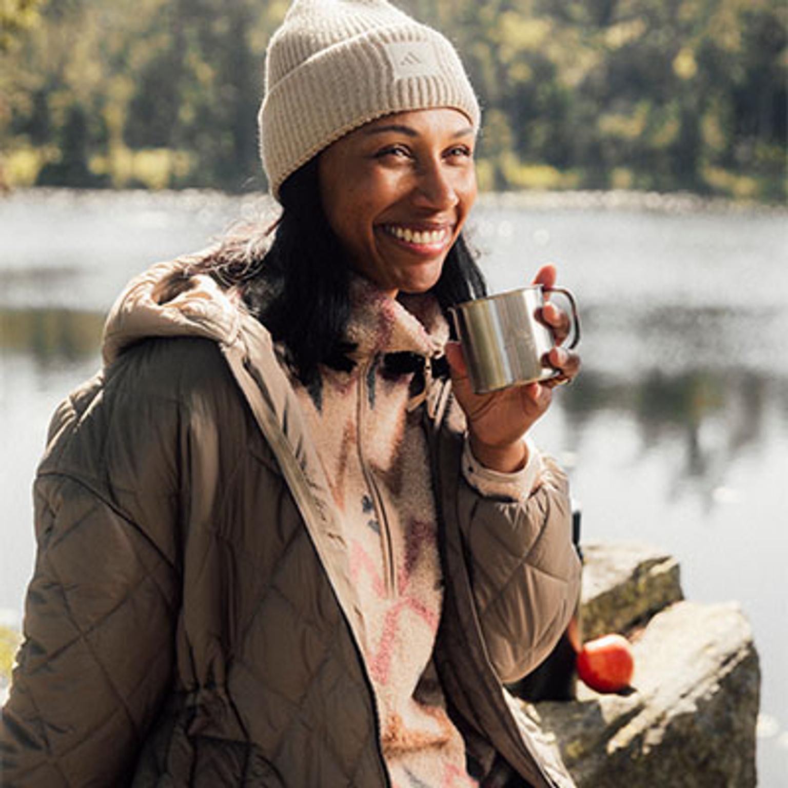 a woman is sitting on a rock holding a cup of coffee .