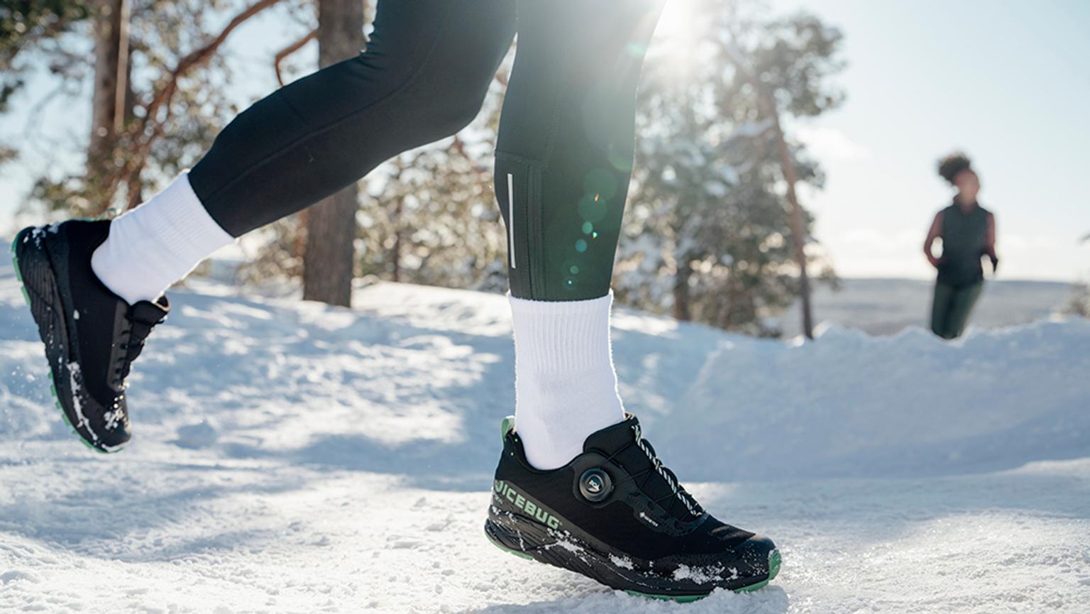 a person wearing black shoes is running in the snow .