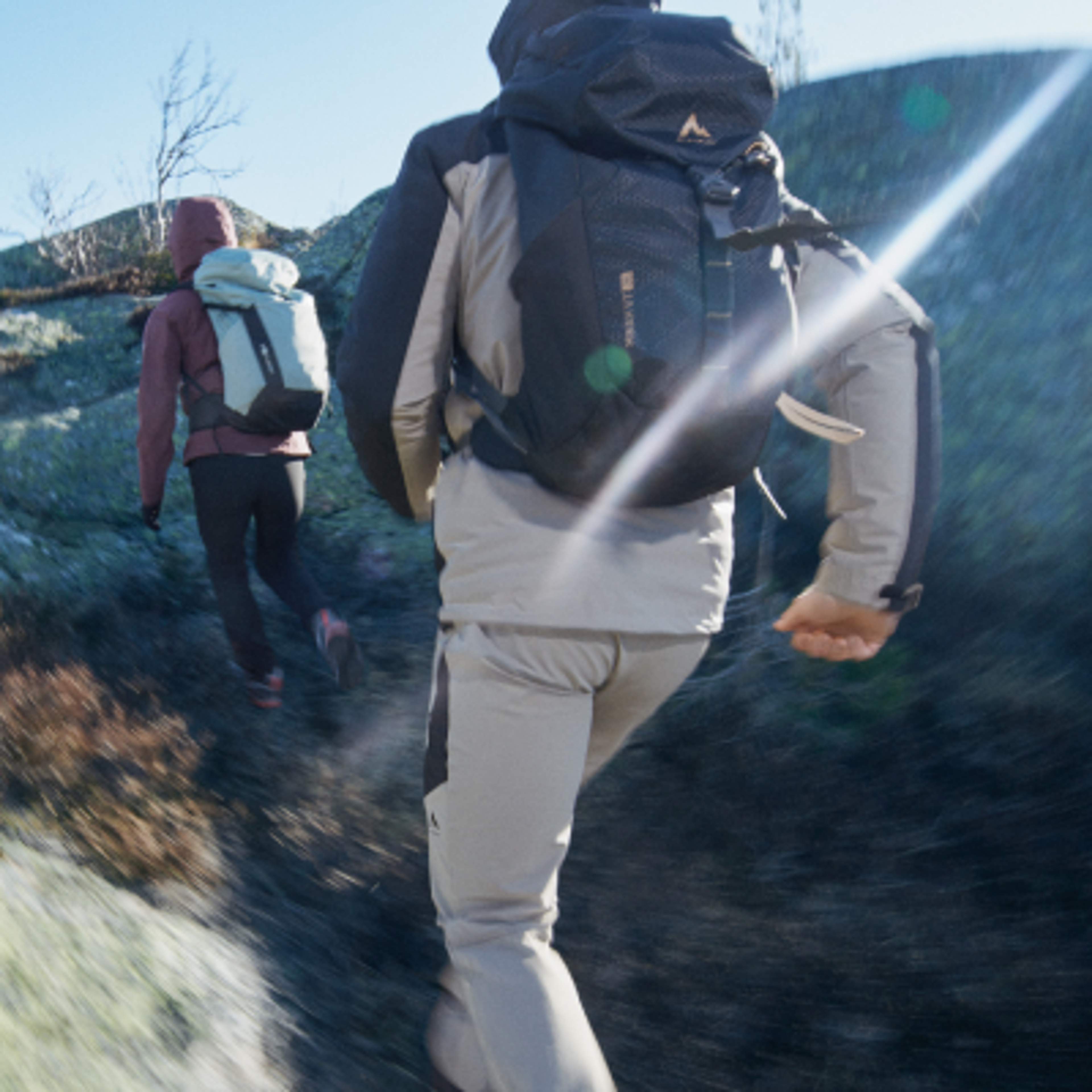 a man and a woman are hiking up a hill .
