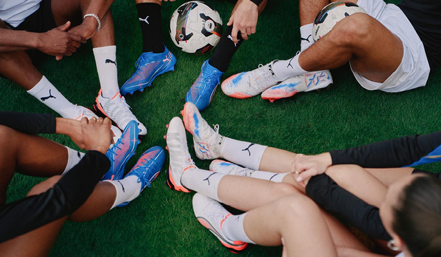 a group of people are sitting in a circle on the grass with soccer cleats and a soccer ball .
