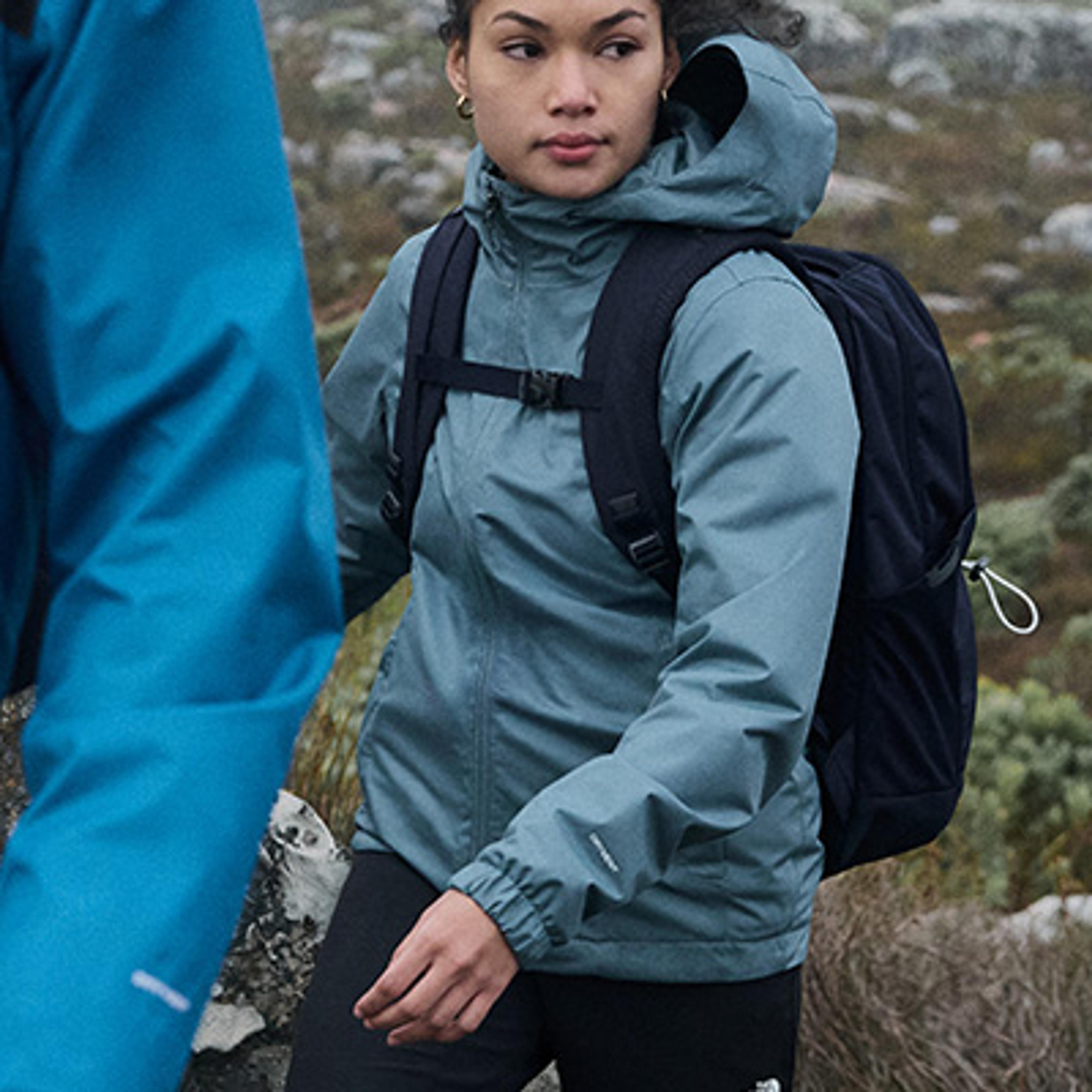 a woman wearing a blue jacket and a black backpack is standing next to a man wearing a blue jacket .