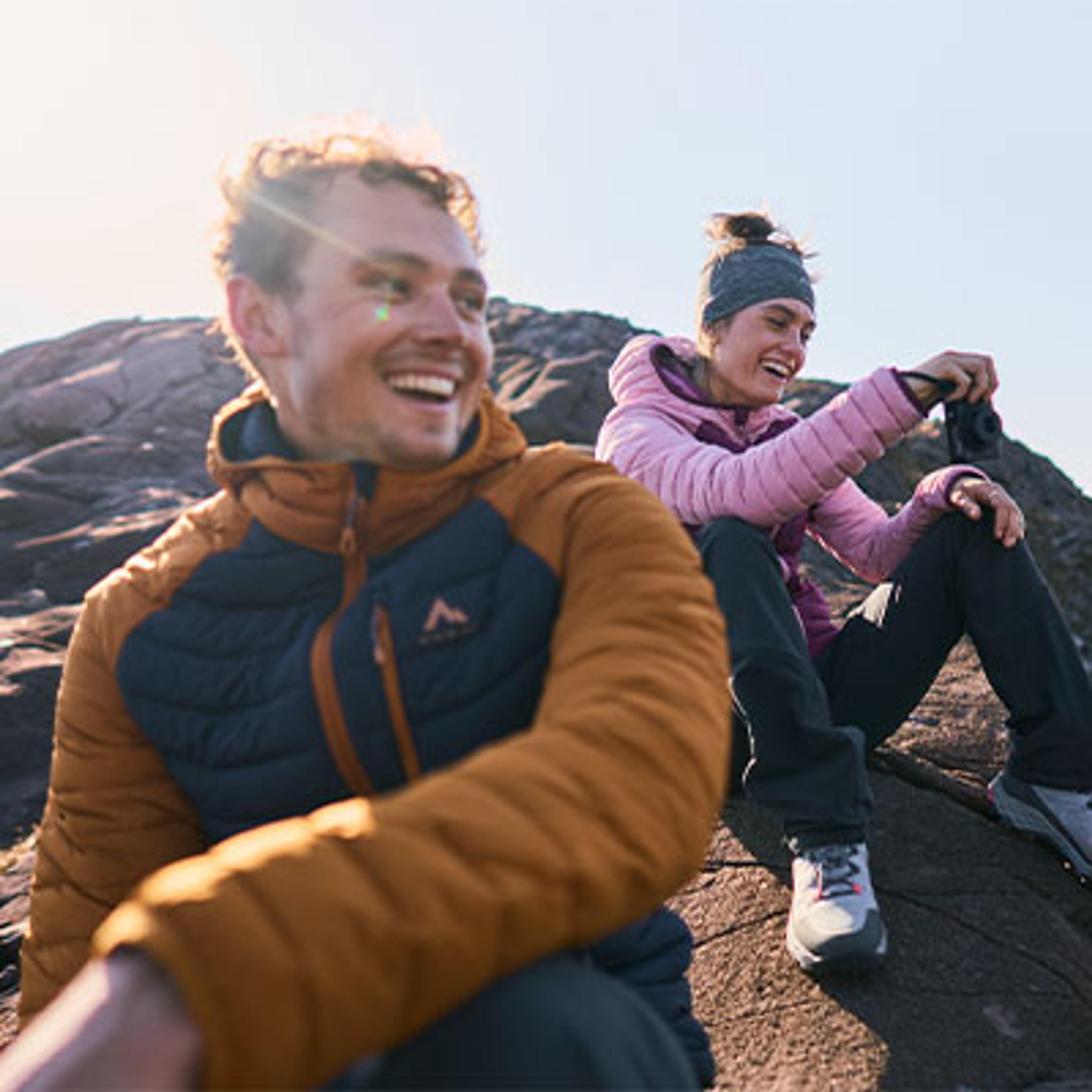 a man and a woman are sitting on a rock on top of a mountain .