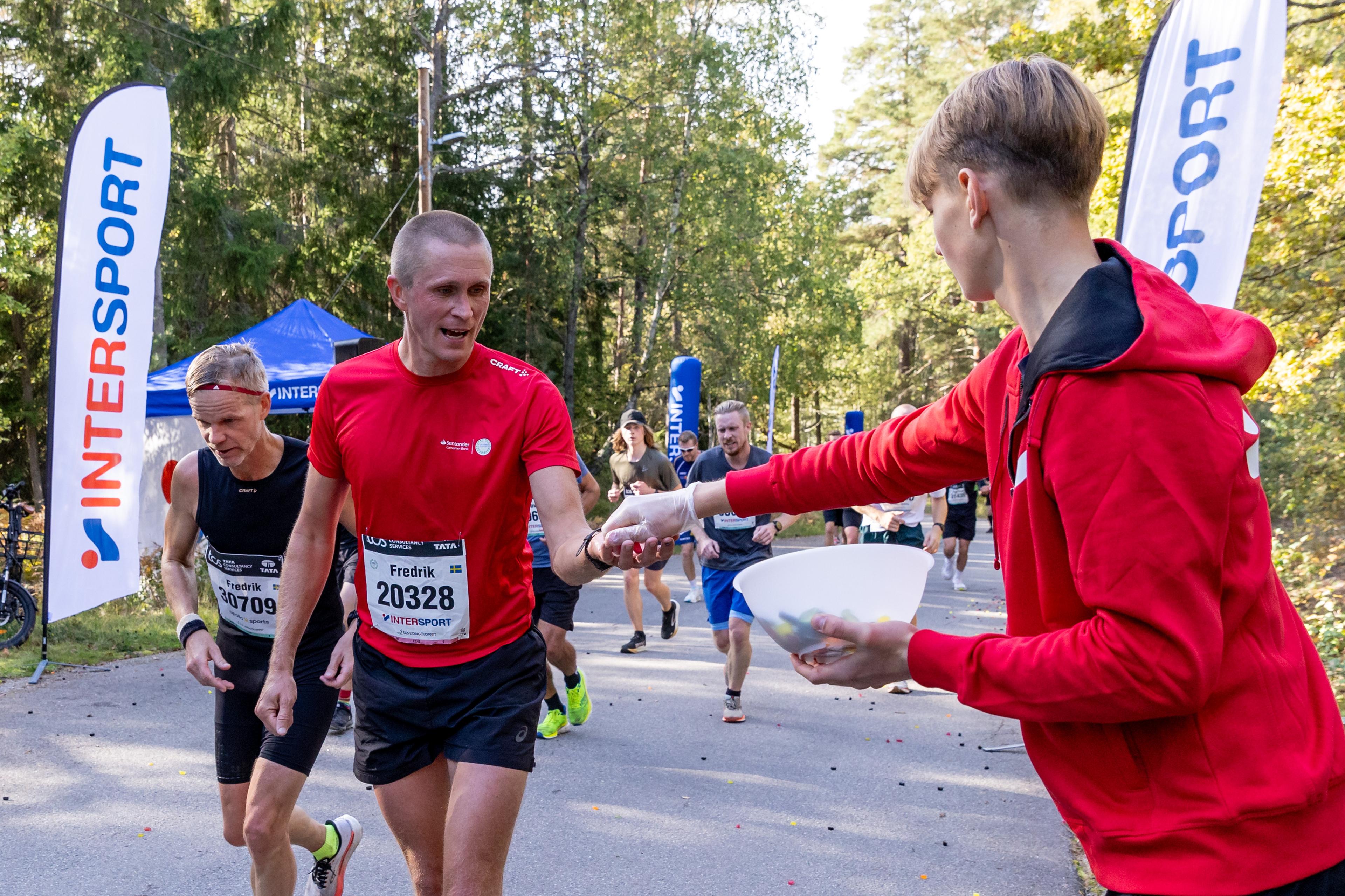 a man is giving water to a group of runners .