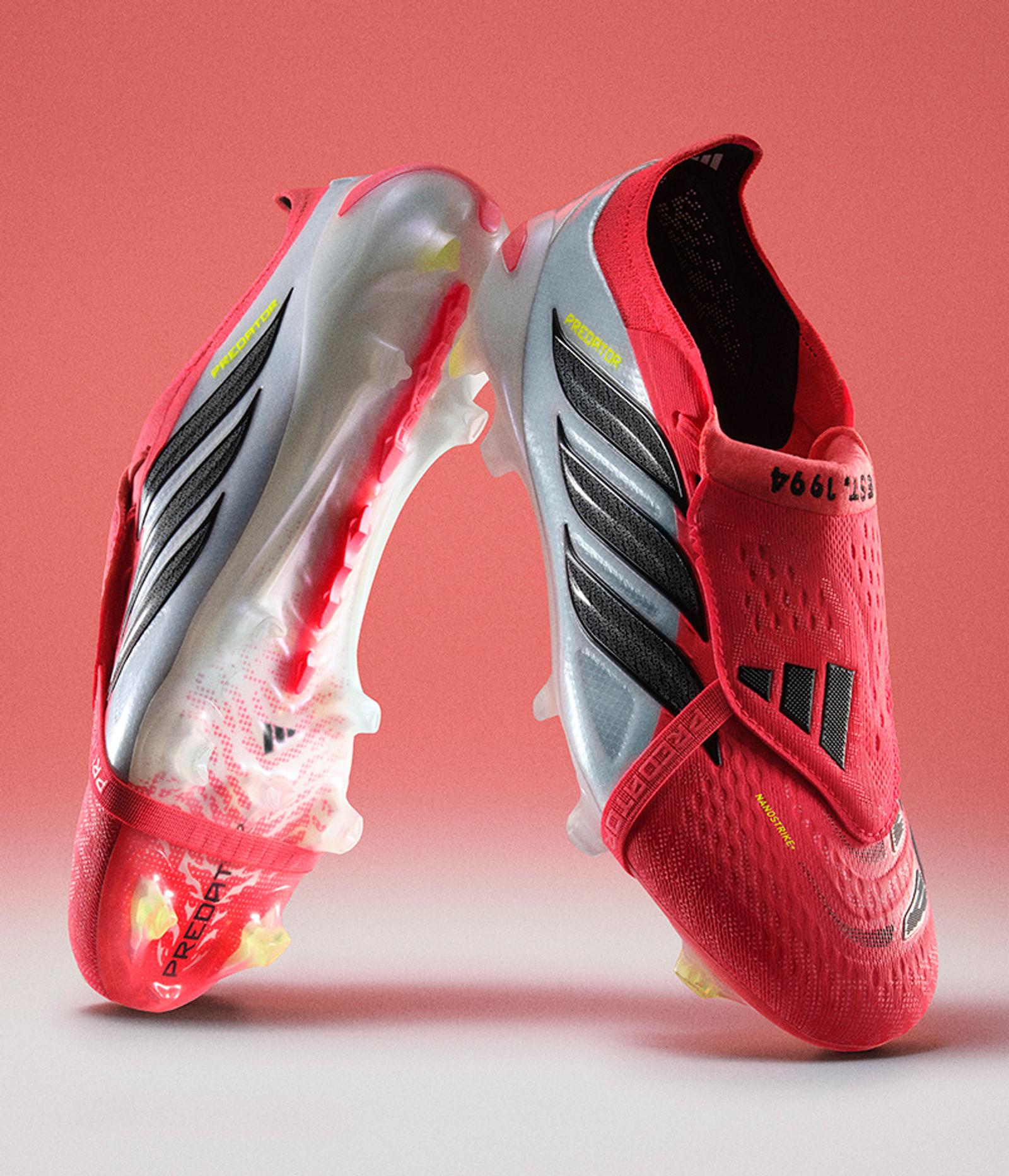 Two red and white Adidas Predator soccer cleats with black stripes, facing each other against a red background.