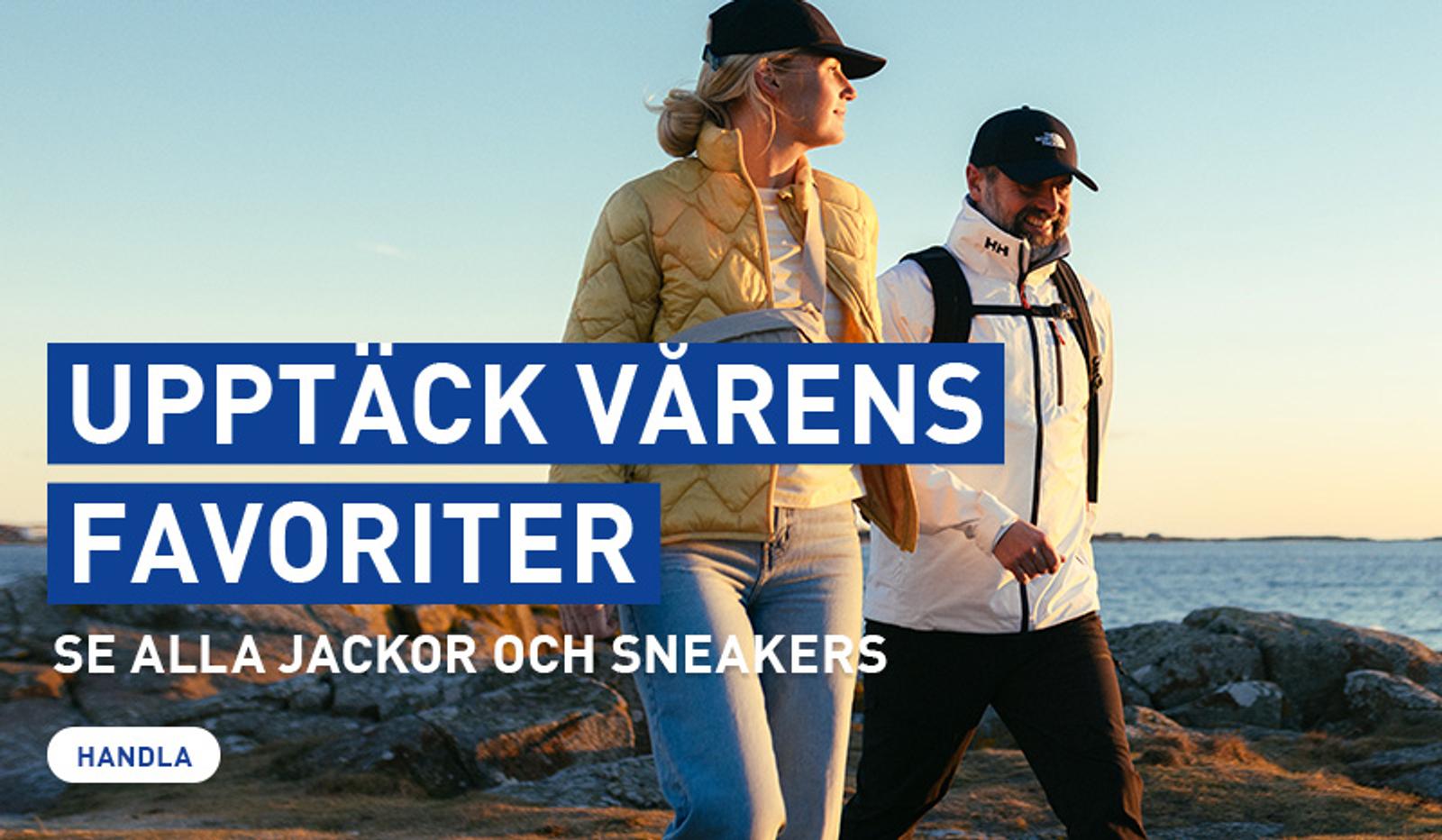 A man and woman in spring jackets and caps walk along a rocky coast. Text: "Discover Spring's Favorites: Jackets and Sneakers."