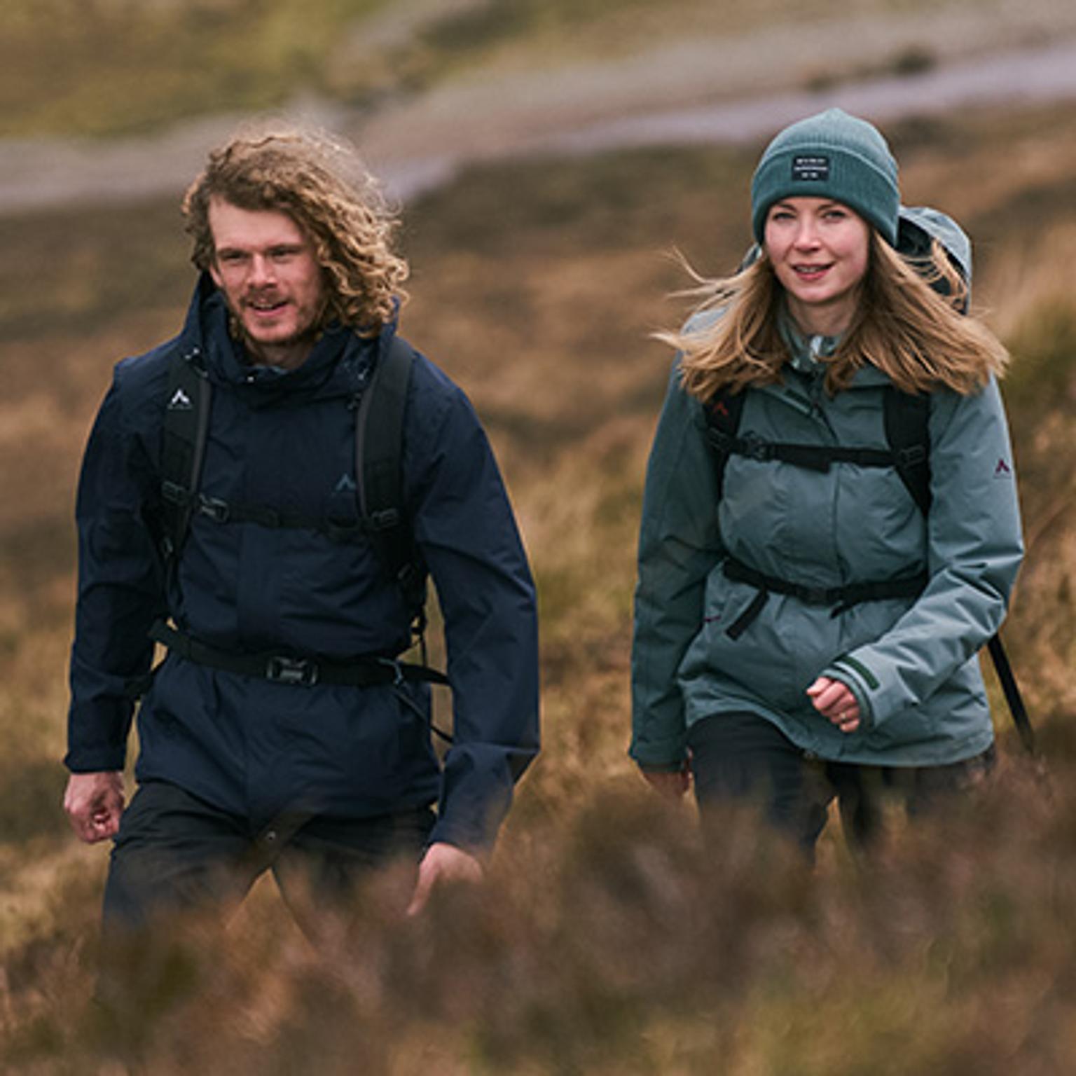a man and a woman are walking through a field .