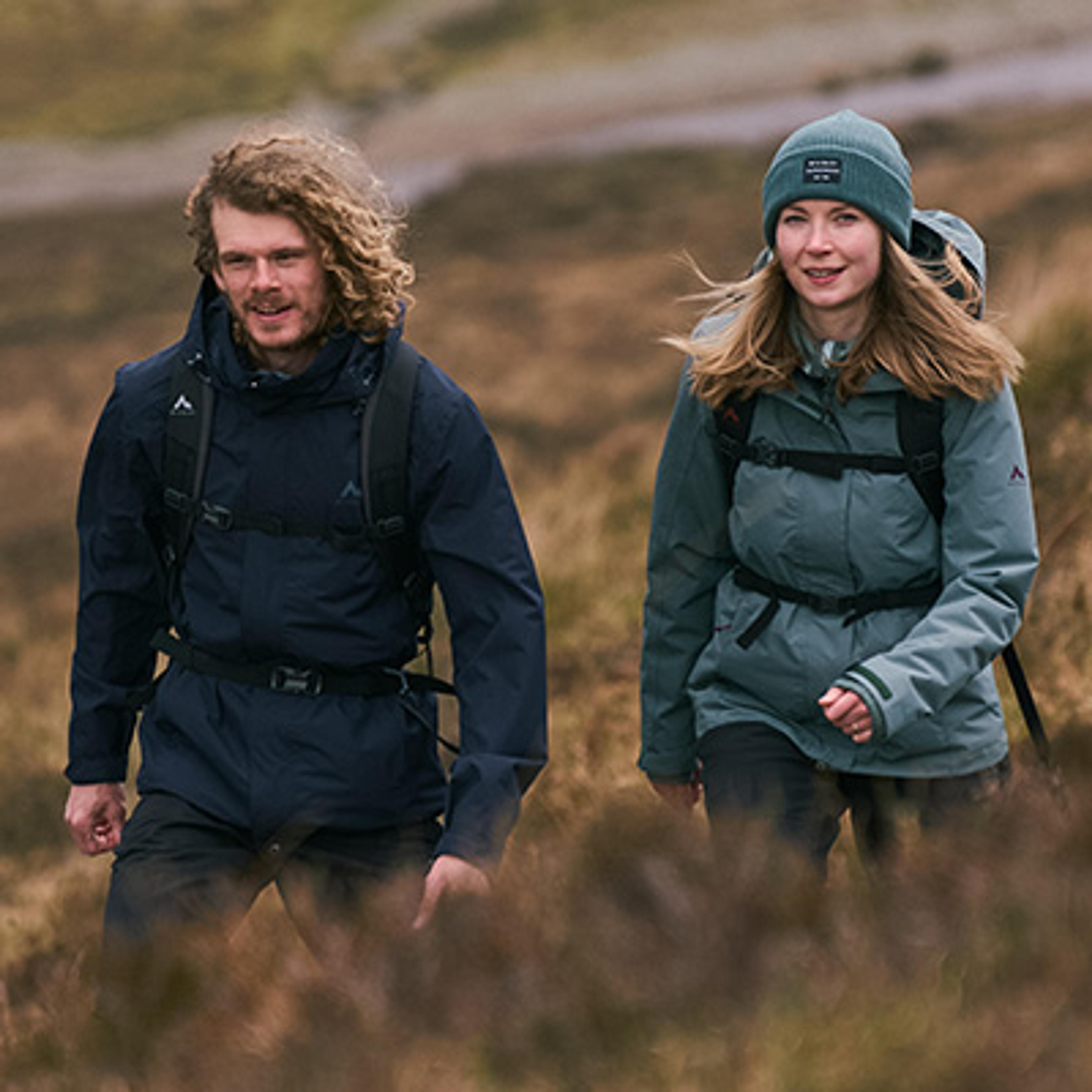 a man and a woman are walking through a field .