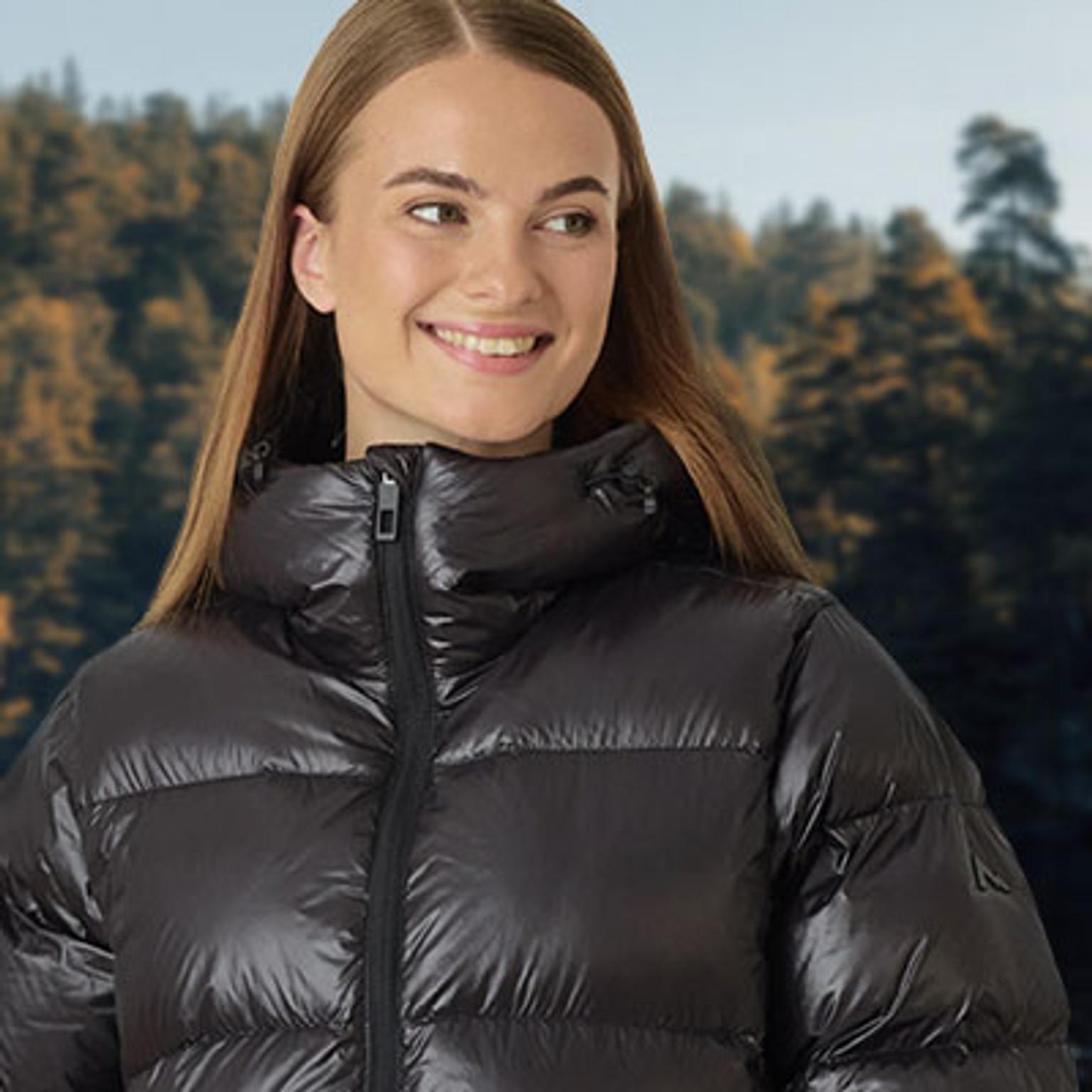 a woman is wearing a black padded jacket and smiling .