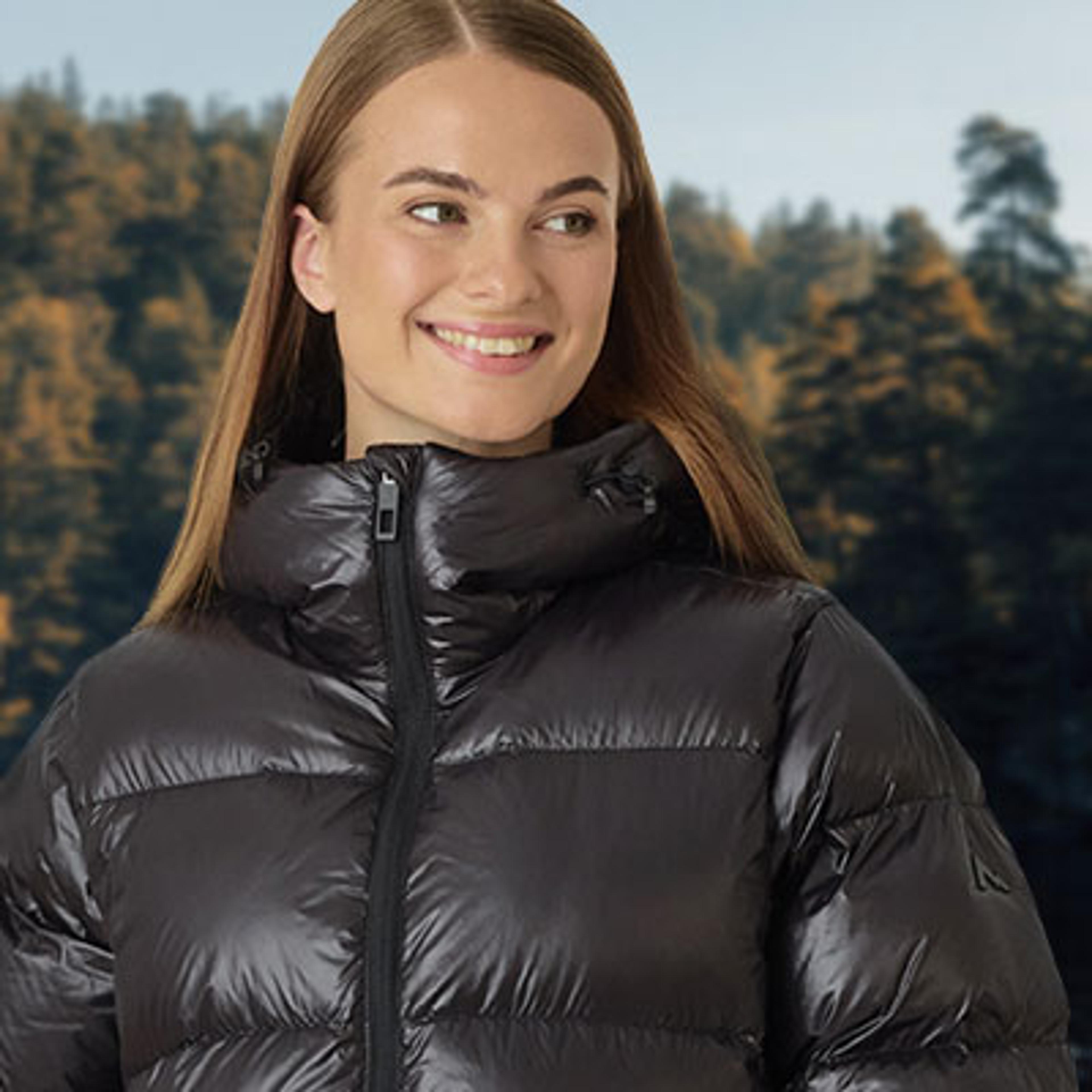 a woman is wearing a black padded jacket and smiling .