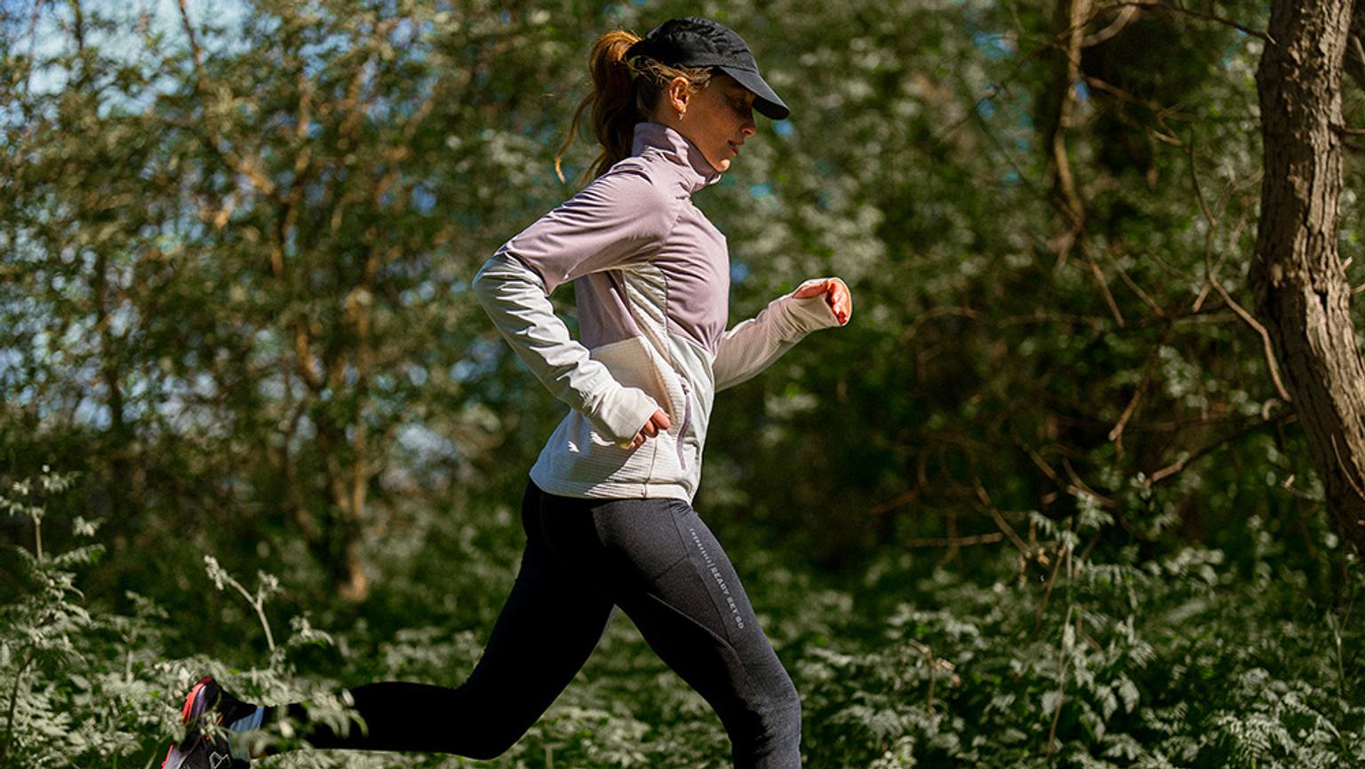 a woman is running through a forest on a sunny day .