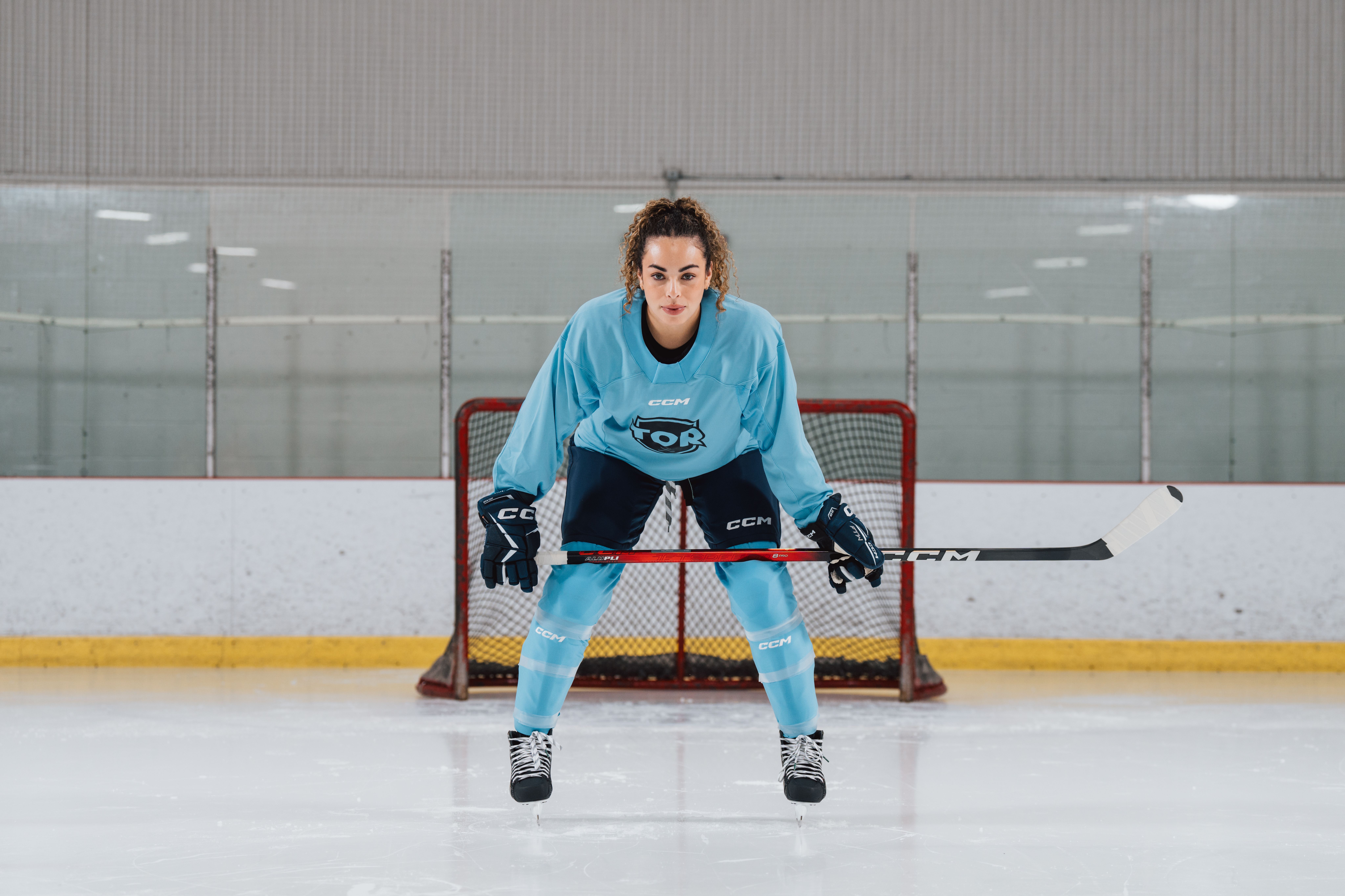 a woman is holding a hockey stick in front of a goal .