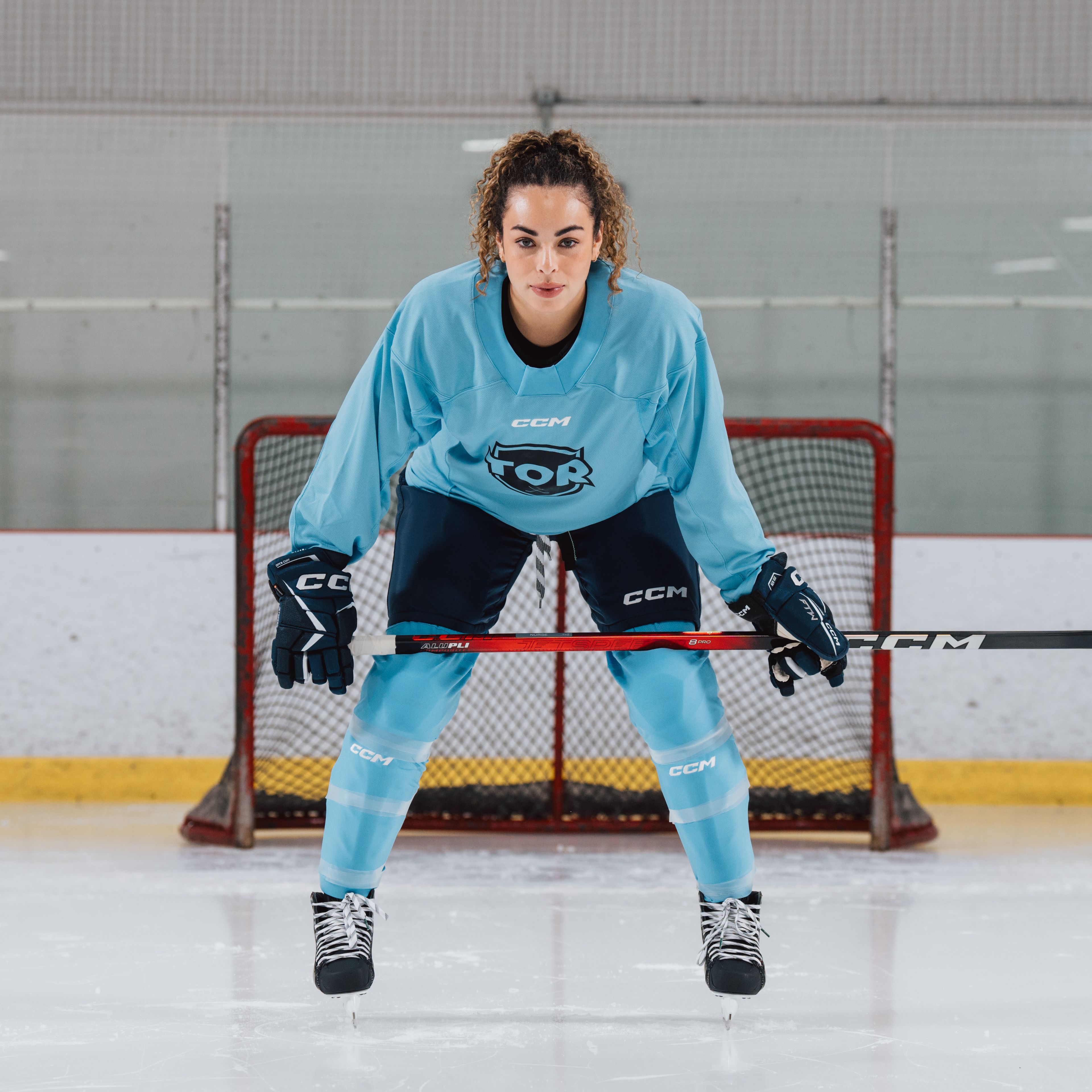 a woman is holding a hockey stick in front of a goal .