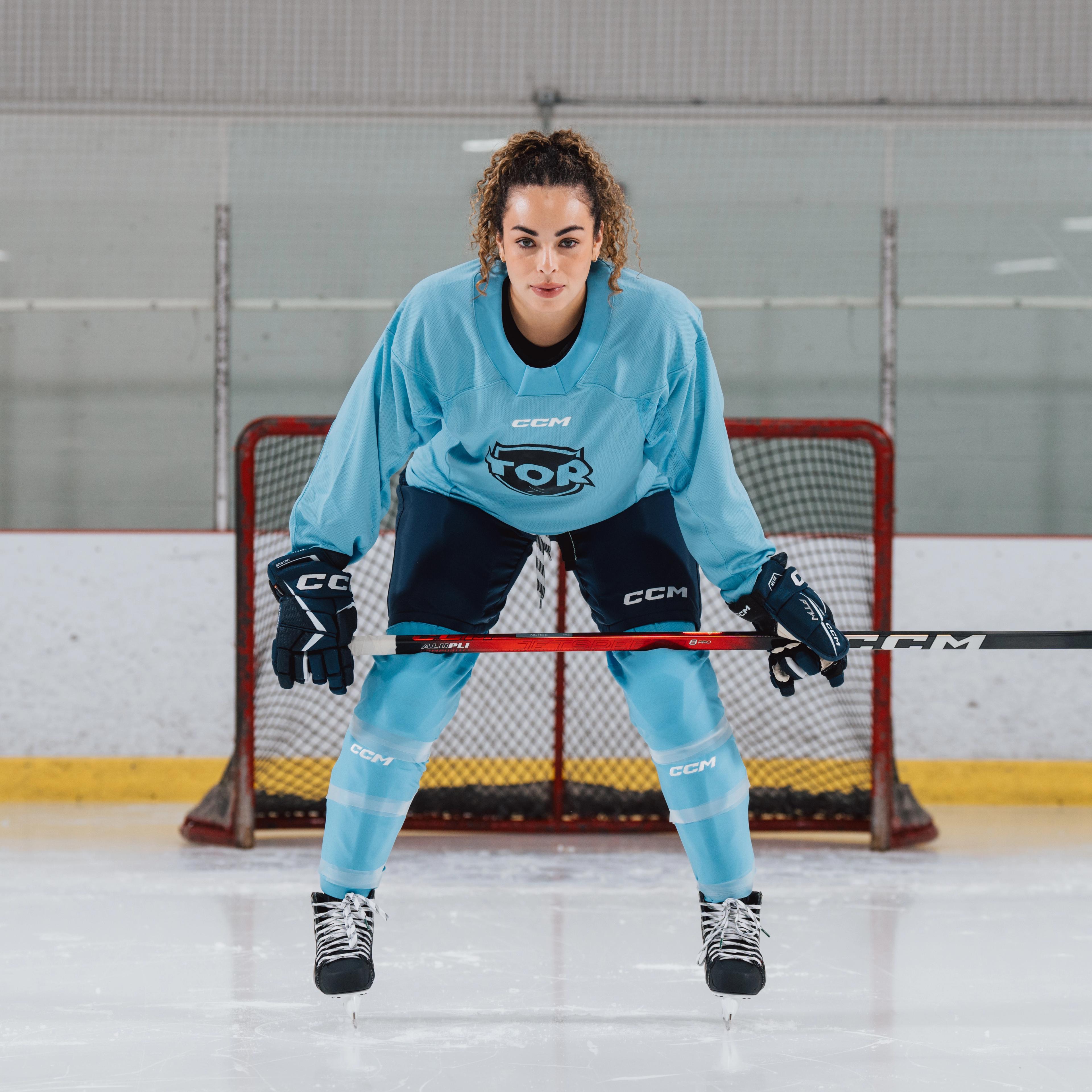 a woman is holding a hockey stick in front of a goal .