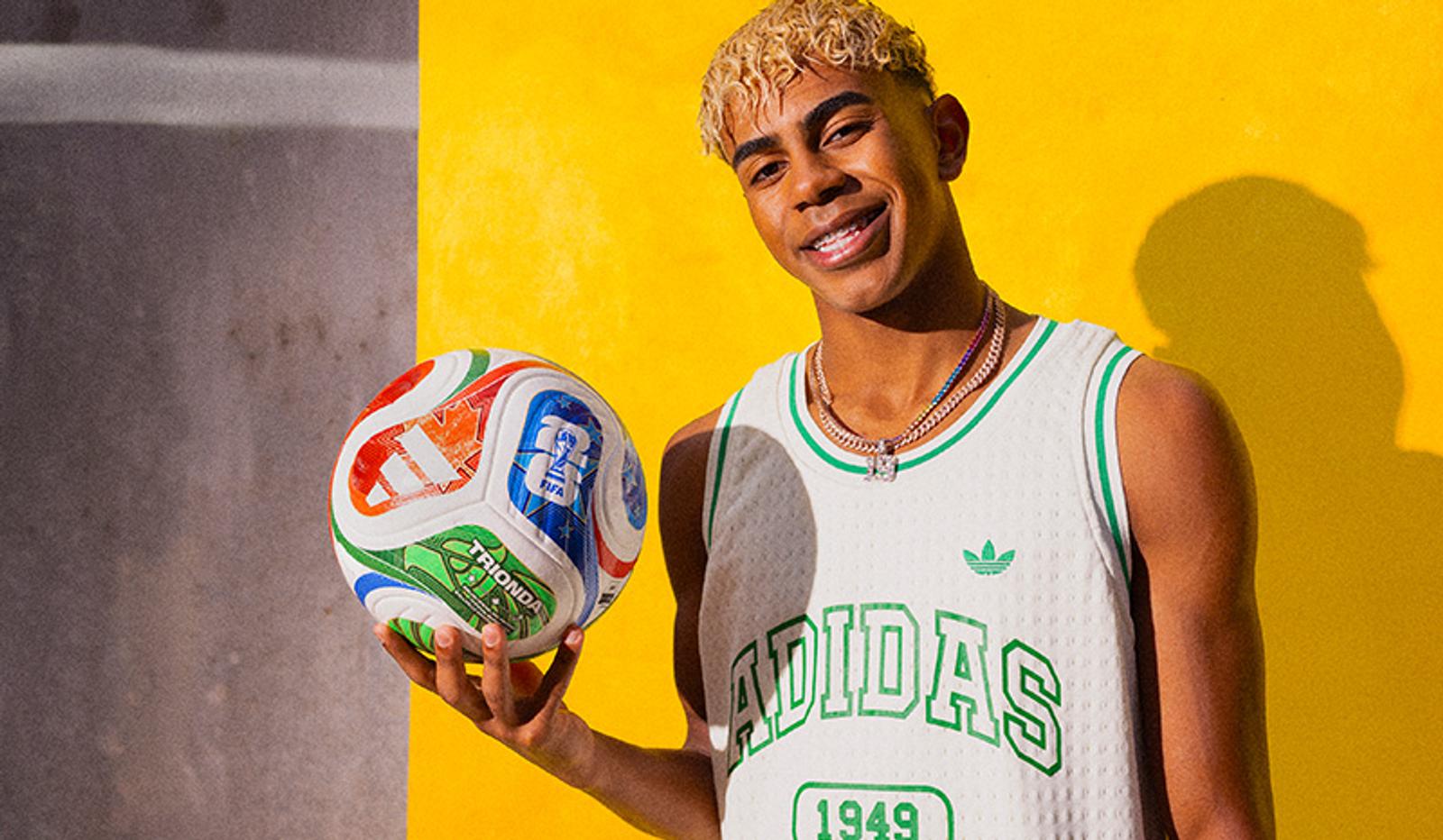 a young man in an adidas jersey is holding a soccer ball .