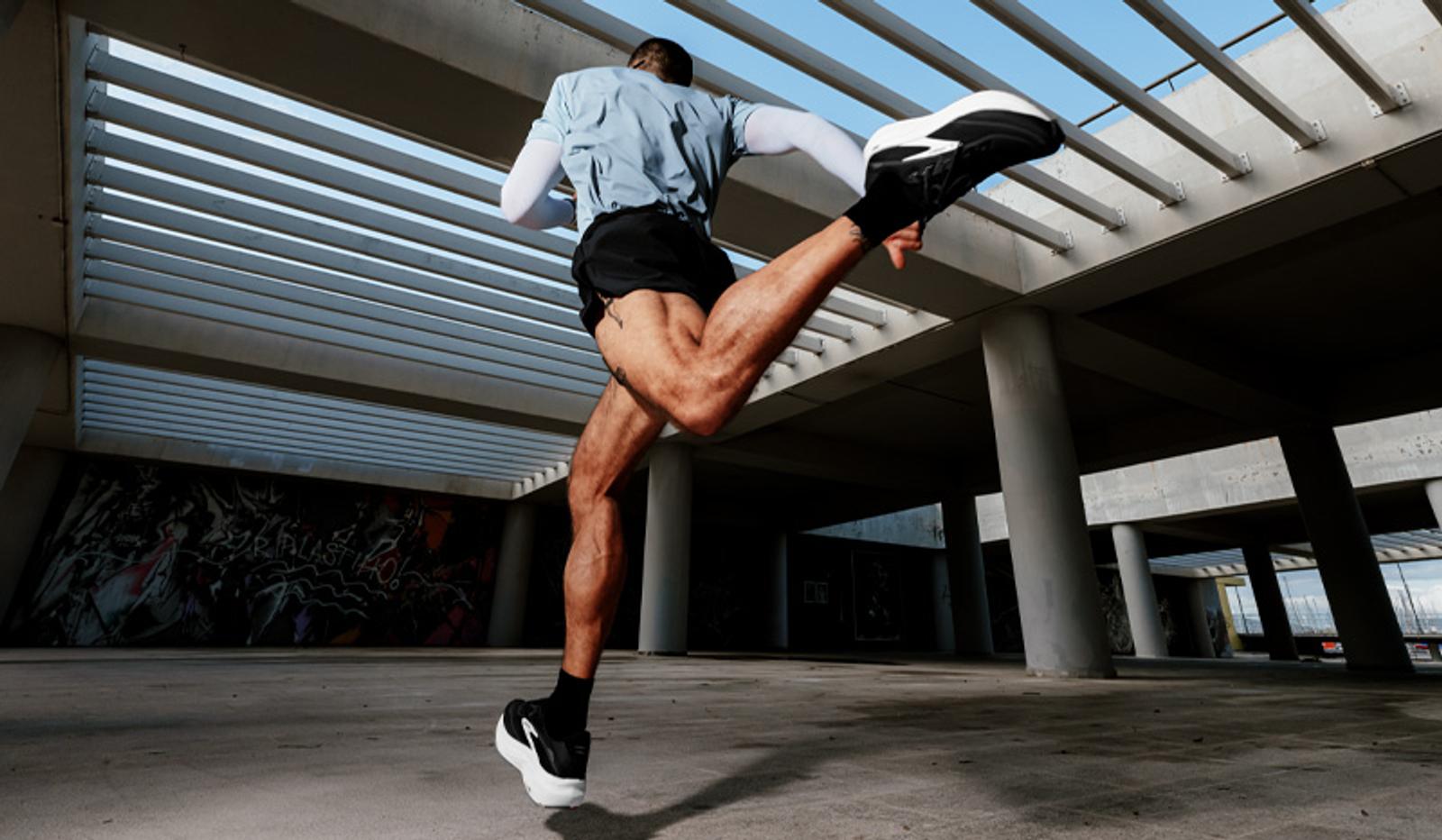 A person in athletic wear running through a concrete structure, viewed from a low angle.