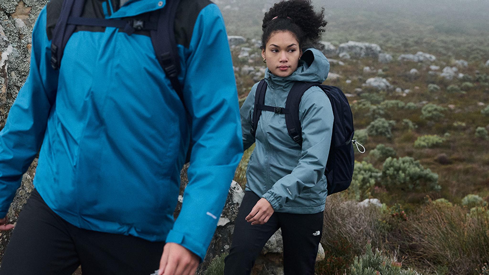 a man and a woman are hiking up a hill .